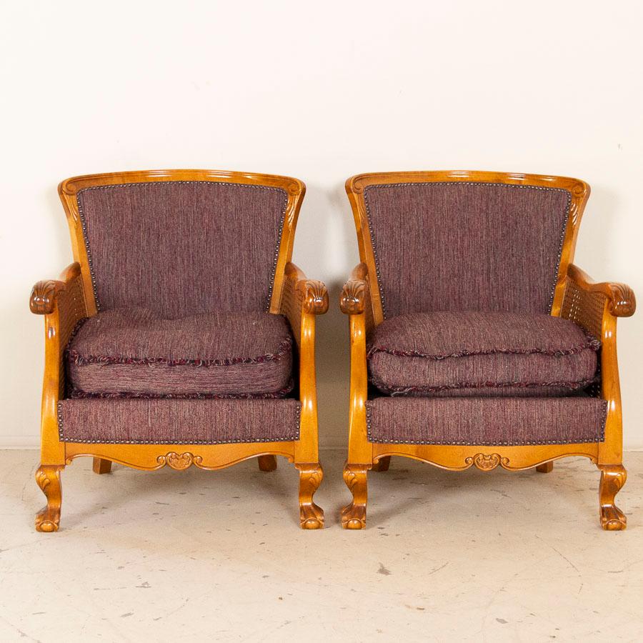 Casual and comfortable, these Swedish armchairs have graceful curves which add an air relaxed refinement to the pair. The sides are a woven rattan, with hand carved decorative elements in the arms, feet and center front. The seat cushions are loose,