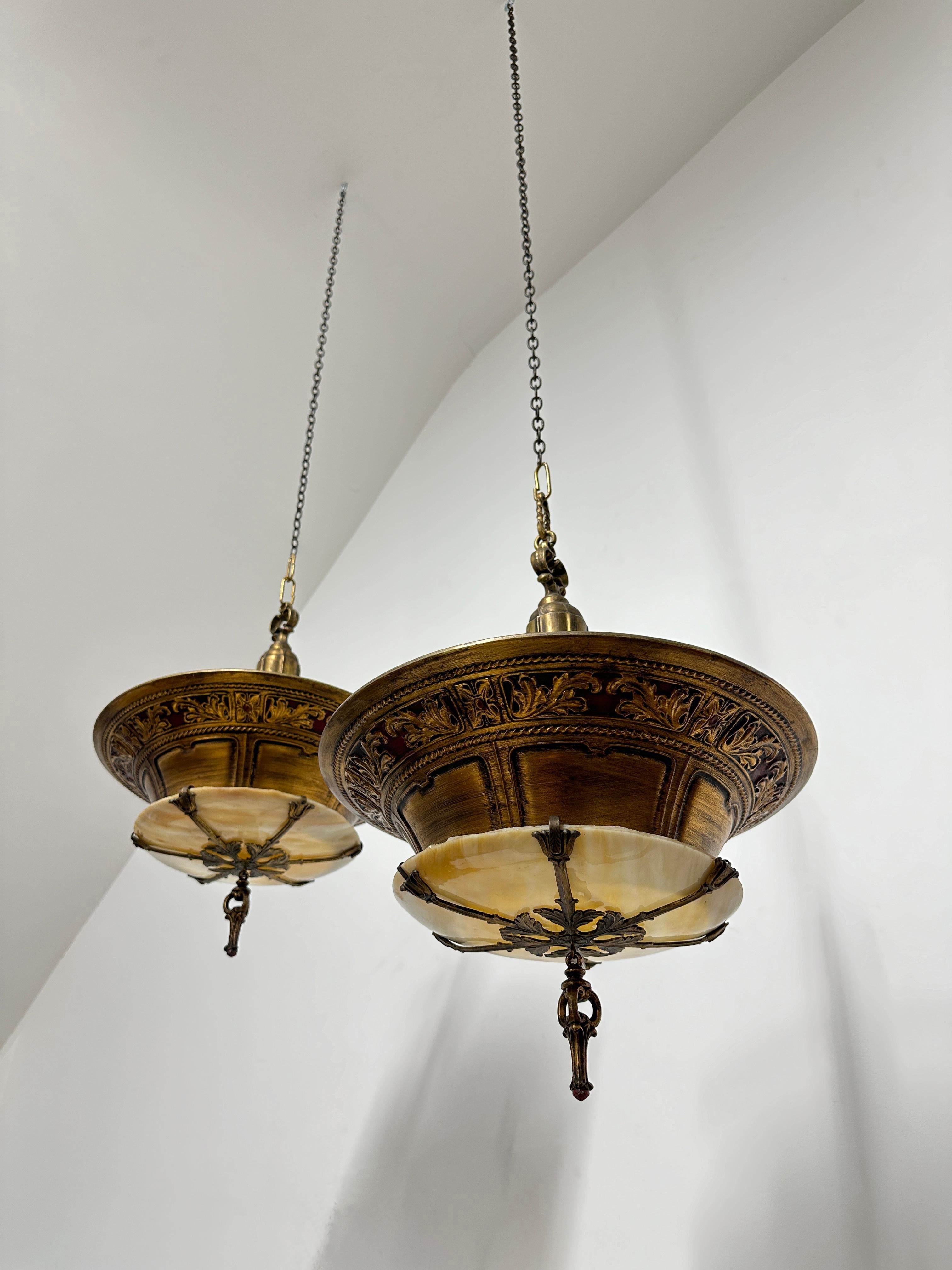 - Une paire incroyablement rare de suspensions de plafond en Duplexalite, américaine vers 1920. 
- Il s'agit apparemment d'un de leurs modèles standard comprenant un boîtier à douille et trois bras métalliques fins qui soutiennent le grand abat-jour