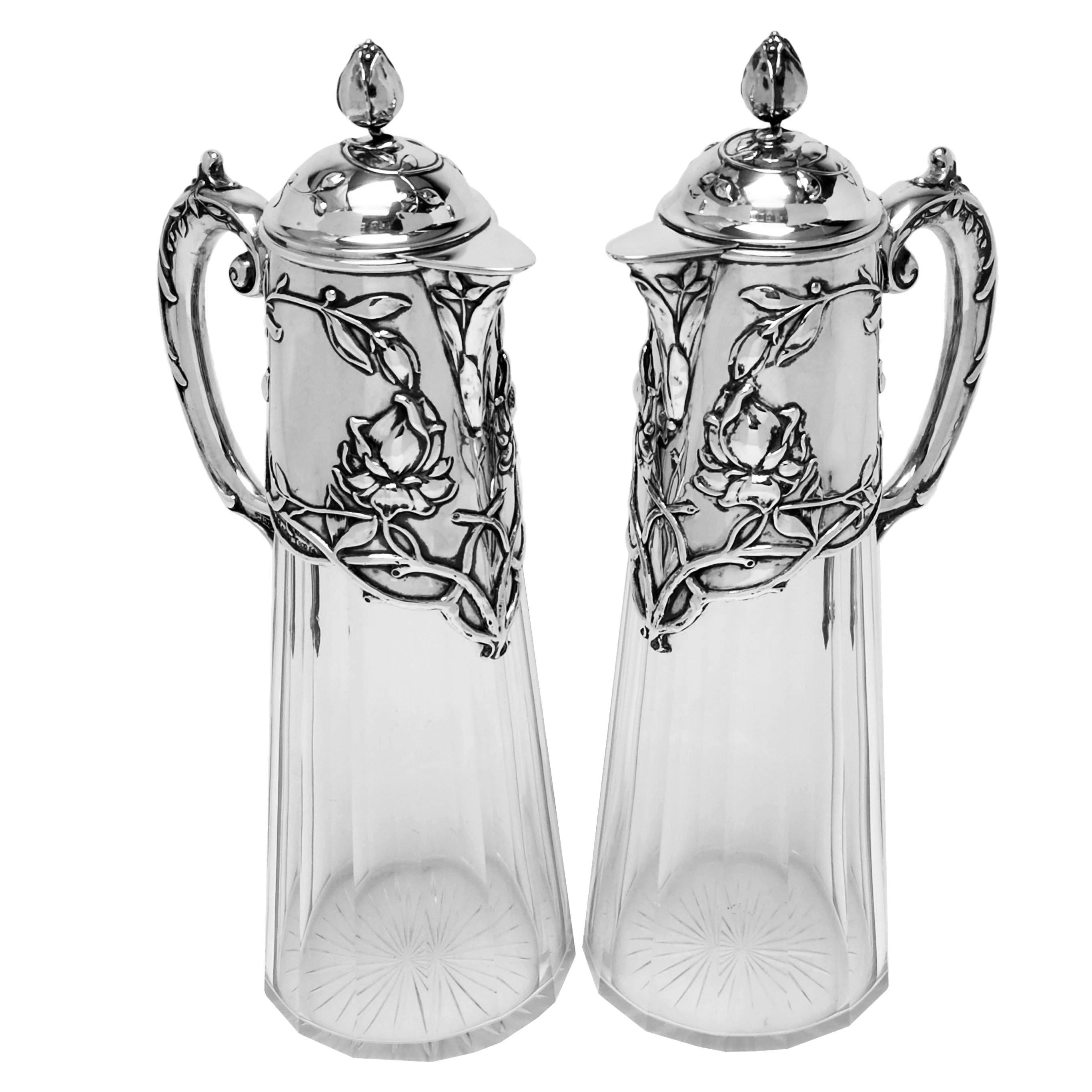 A pair of elegant antique German silver & cut glass claret jugs with classic Jugendstil design elements. The Silver neck, lid and handles of the Wine Jugs feature beautiful Art Nouveau floral and foliate designs and the Lid has a stylised floral