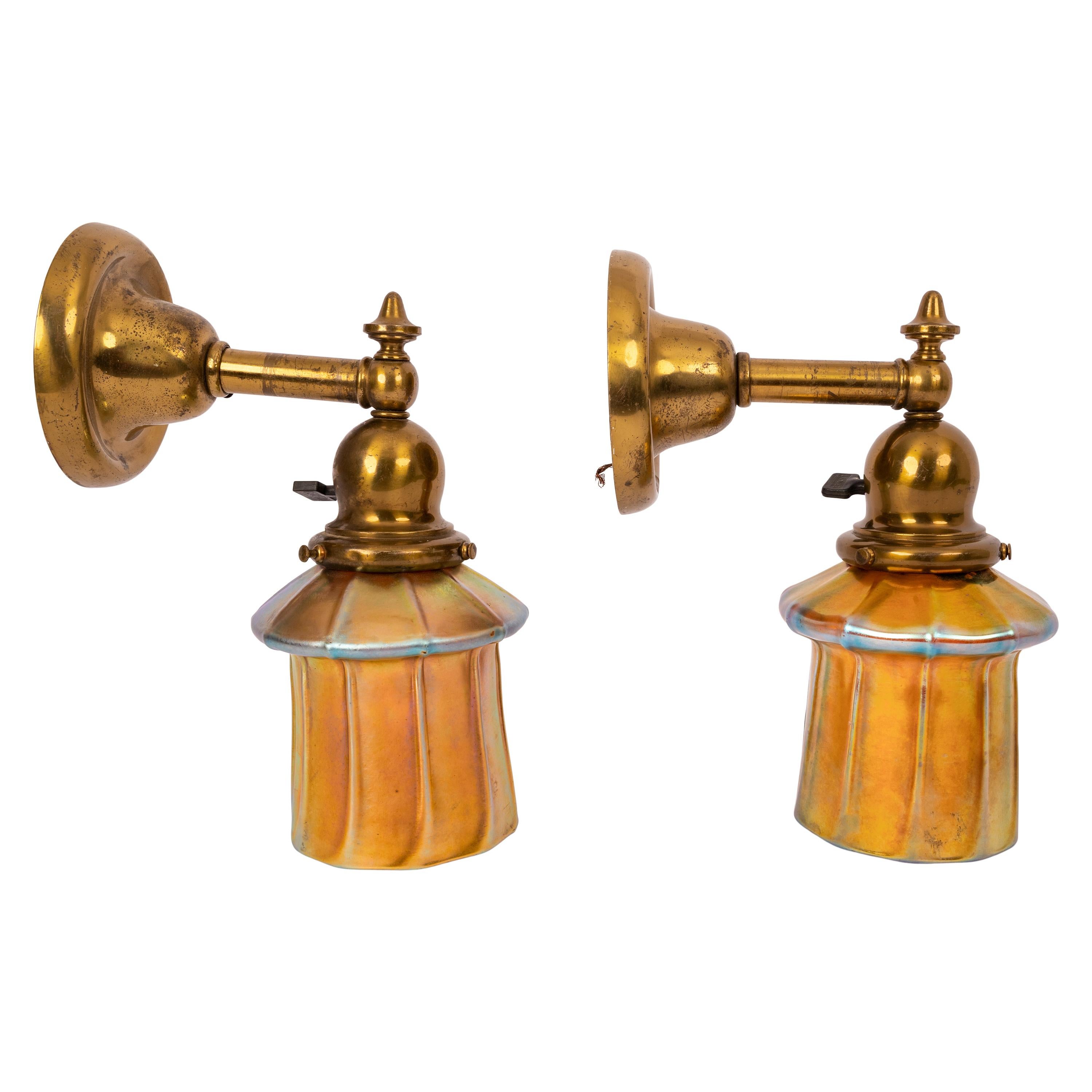A good pair of antique Arts & Crafts/ Mission Steuben gold Aurene glass shades and brass sconces, circa 1910.
The sconces having the original brass wall mounts with circular backplates, the sconces having circular posts that connect to the domed