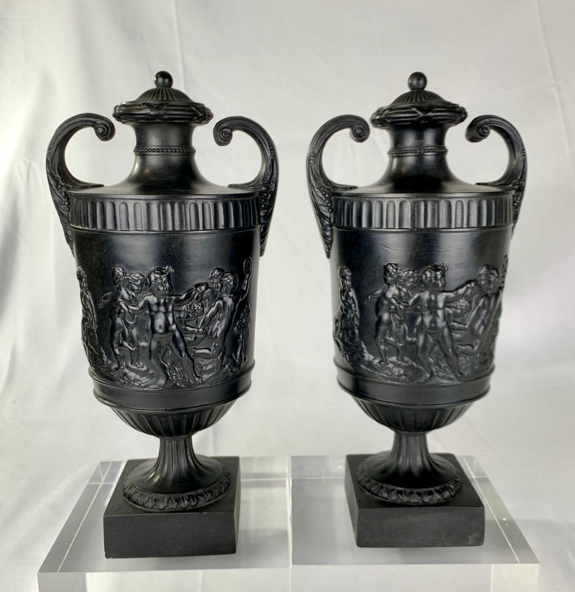 This exceptional pair of antique black basalt vases was made by Wedgwood & Bentley in the late 18th century, circa 1775. 
The vases are sculpted in deep solid relief with bacchanalian boys in lively motion, a classical motif symbolizing liberation