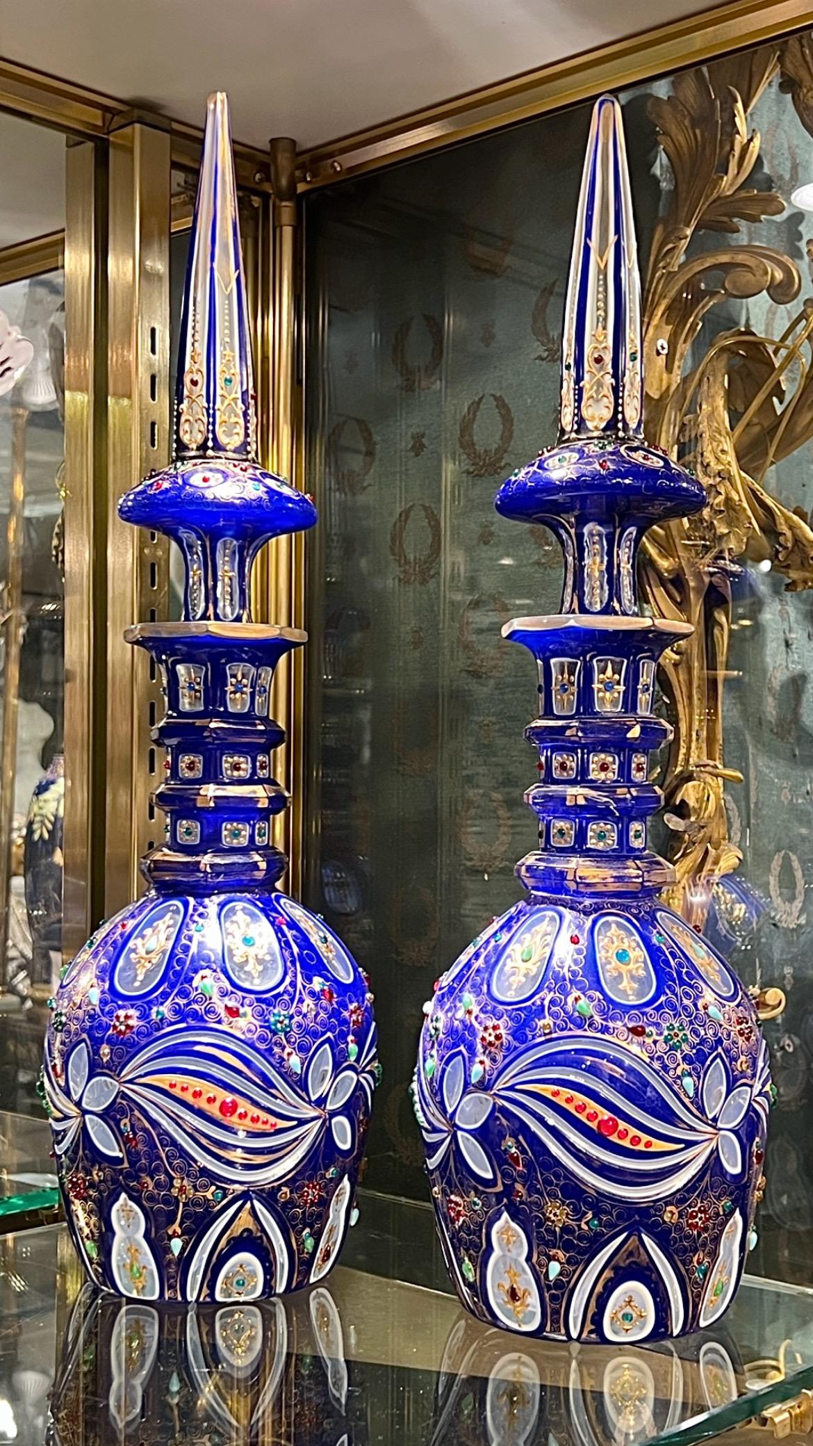 Pair of  (early 20th century) Bohemian bottles with large stoppers, ie. decanters, exquisitely made for the Middle Eastern market, in royal blue and white glass cut to clear glass, with beautiful gilt decorations and applied glass jewels.  Each 21
