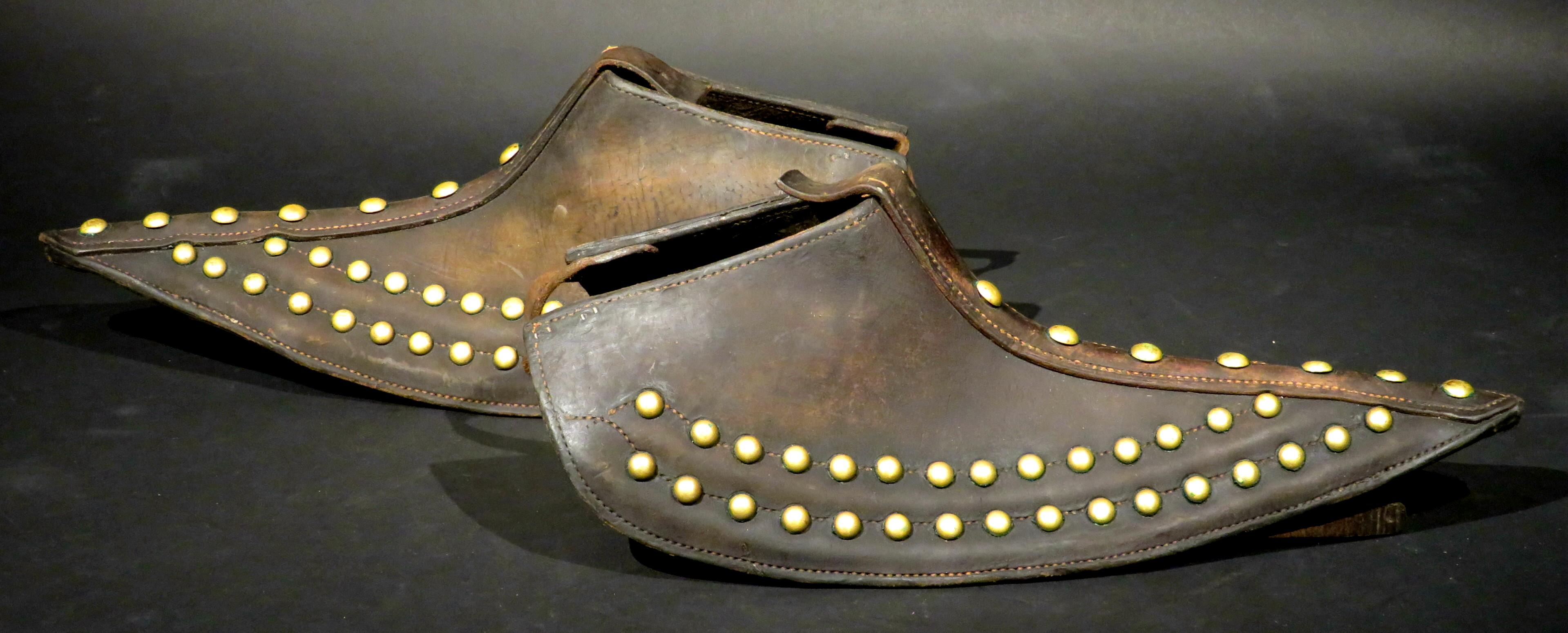 Tapaderos (stirrup covers) were used by ranchers when herding cattle in the brush and open field.
Made of stitched heavy gauge leather and decorated with applied brass studs, both retaining their original adjustable straps & metal clasps.