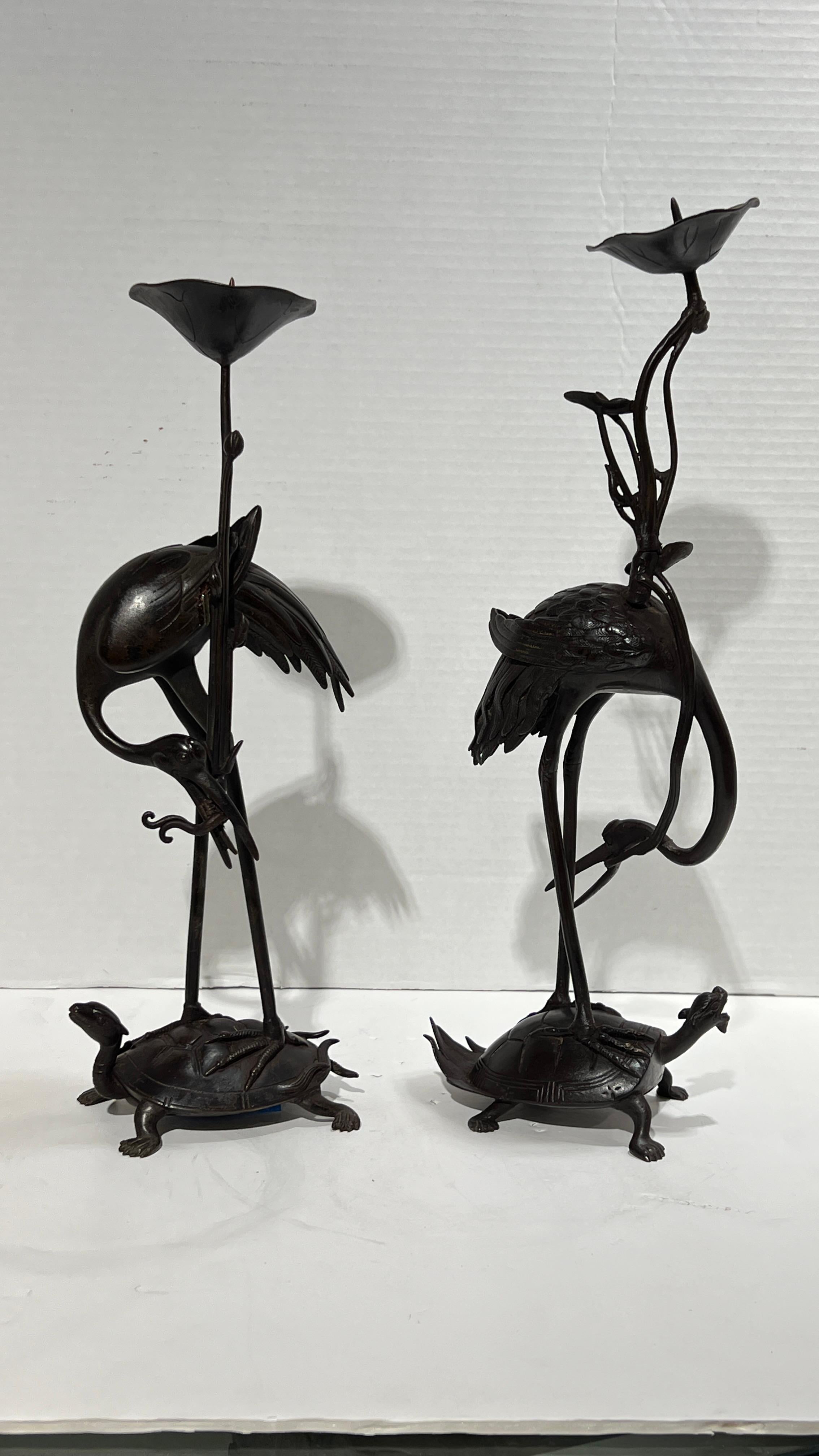 Paire de bougeoirs japonais d'époque Meiji du XIXe siècle en bronze patiné, représentant des grues (ou des hérons) debout sur des tortues miniatures.