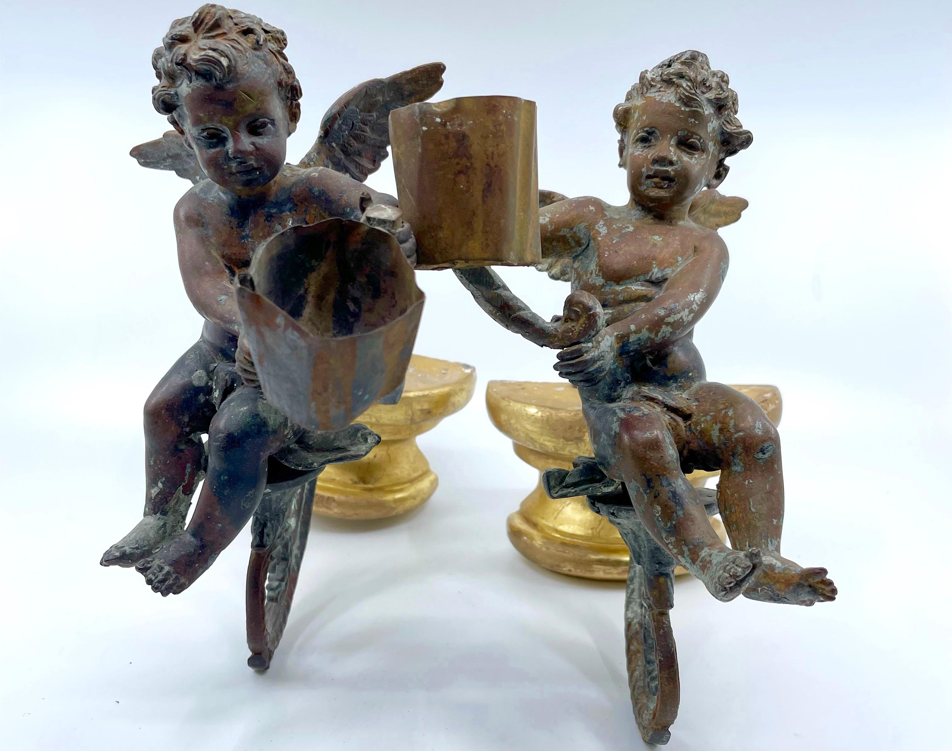 Pair antique bronze patinated angel putti sconces. Italian late 17th century bronze putti with exceptional modeling seated on scrolled arms each extending a candle holder collar, all supported by later gilt wood consoles for wall attachment. Italy,