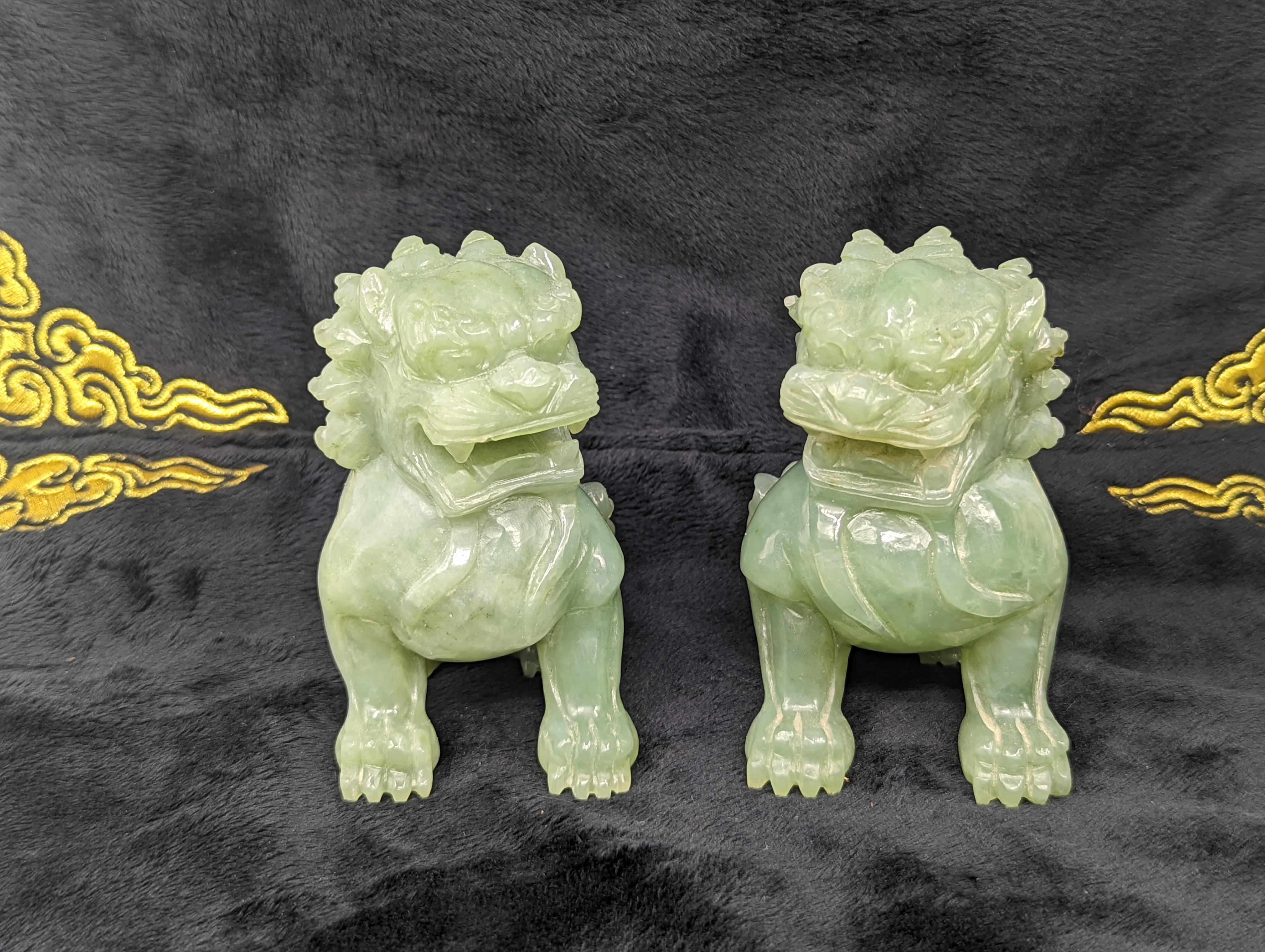 This exquisite pair of celadon jade guardian lions hails from the early Republic of China period, a testament to the era's craftsmanship. The lions are intricately carved from high-quality celadon jade, a material revered for its subtle, pale green