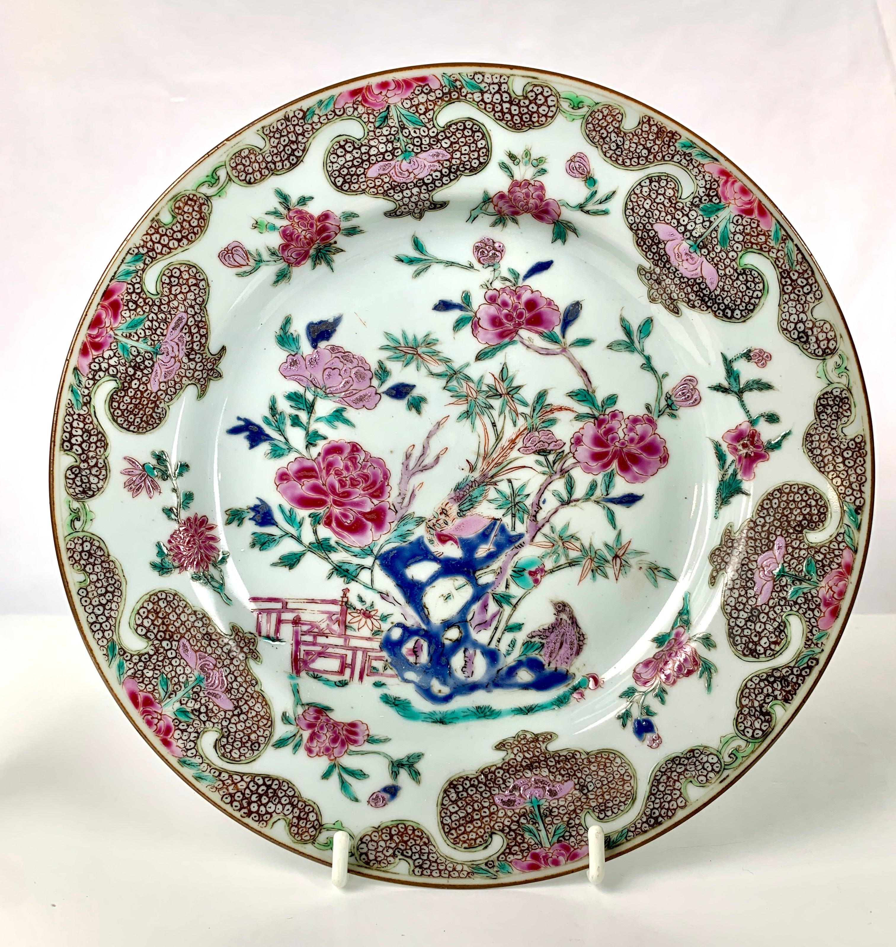 The combination of colors is marvelous!
In the center of each plate, we see a hand painted garden with blue rockwork, purple and white peonies, a single pink peony, a pair of long-tailed songbirds, green bamboo, and a red garden fence,
The floral