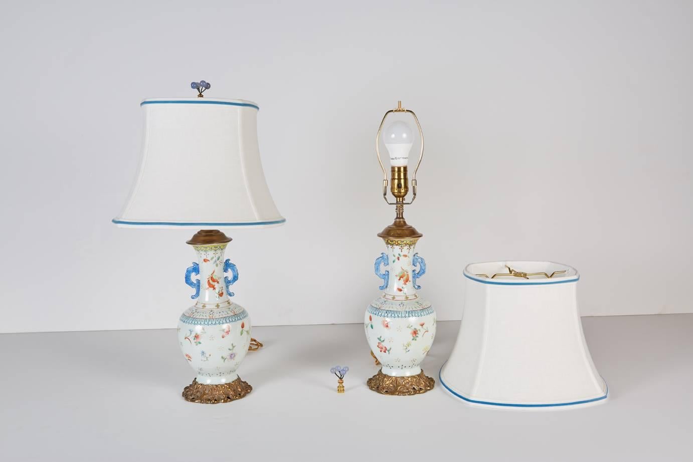 Pair of 19th century Chinese vases resting on later bronze bases with new custom white silk shades trimmed in blue velvet tape and surmounted by blue agate finials.