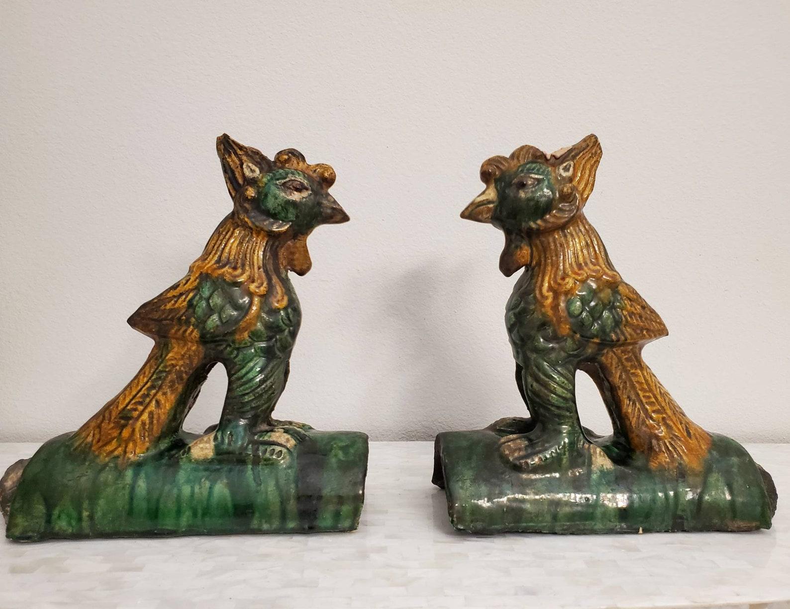 A finely rendered pair of Chinese Qing Dynasty (1644-1910) ceramic architectural roof tiles, glazed in the rich Sancai palette, skillfully modelled as a mythical Phoenix perched atop semi-circular roof tile, the whimsical creature reminiscent of an