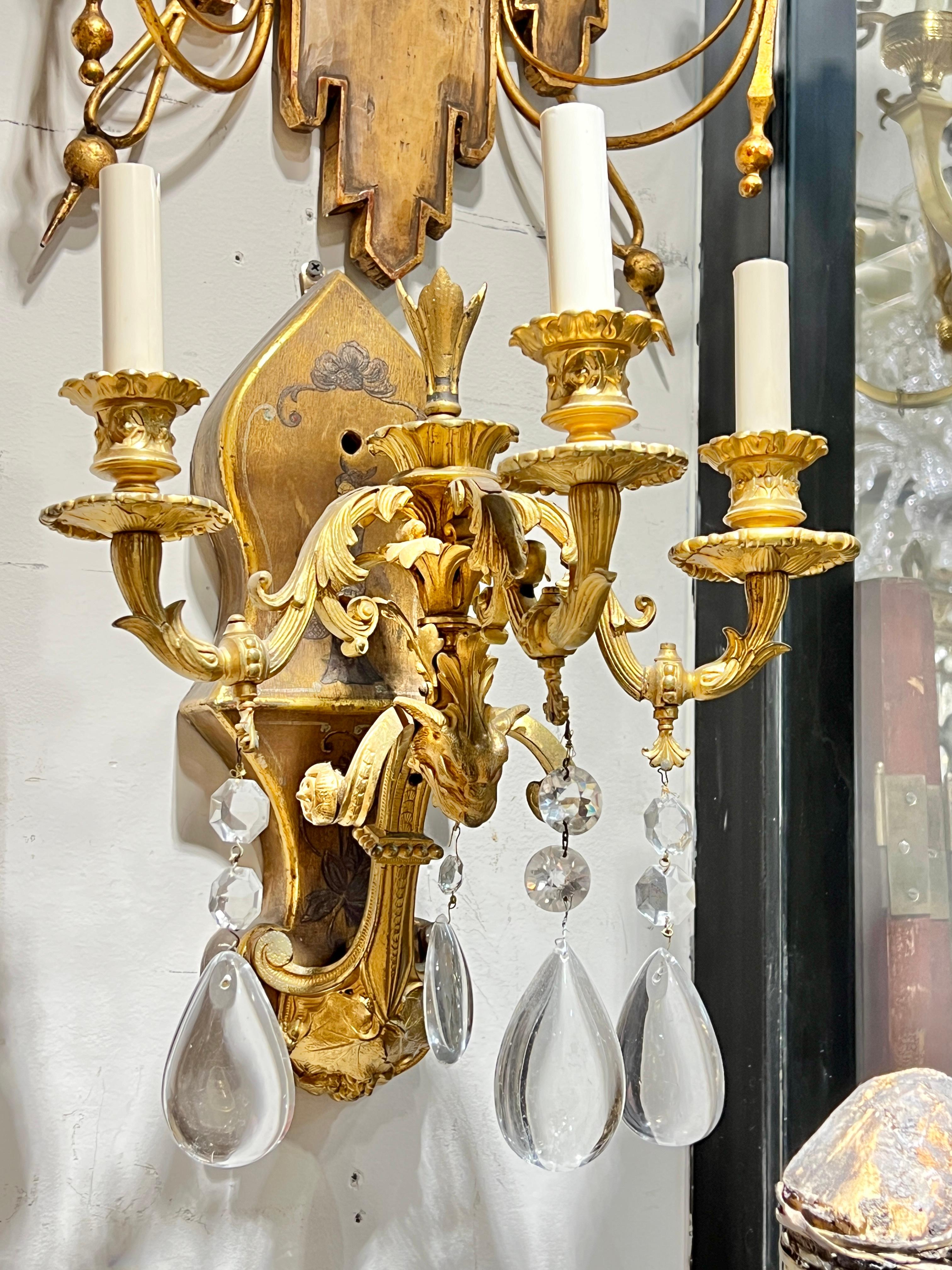 Paire d'appliques à trois lumières en bronze doré de style Chinoiserie avec des plaques de fond en bois sculpté peintes à la main de figures de jeunes filles exotiques.  Avec douilles de taille candélabre et câblage, prêt à l'emploi.