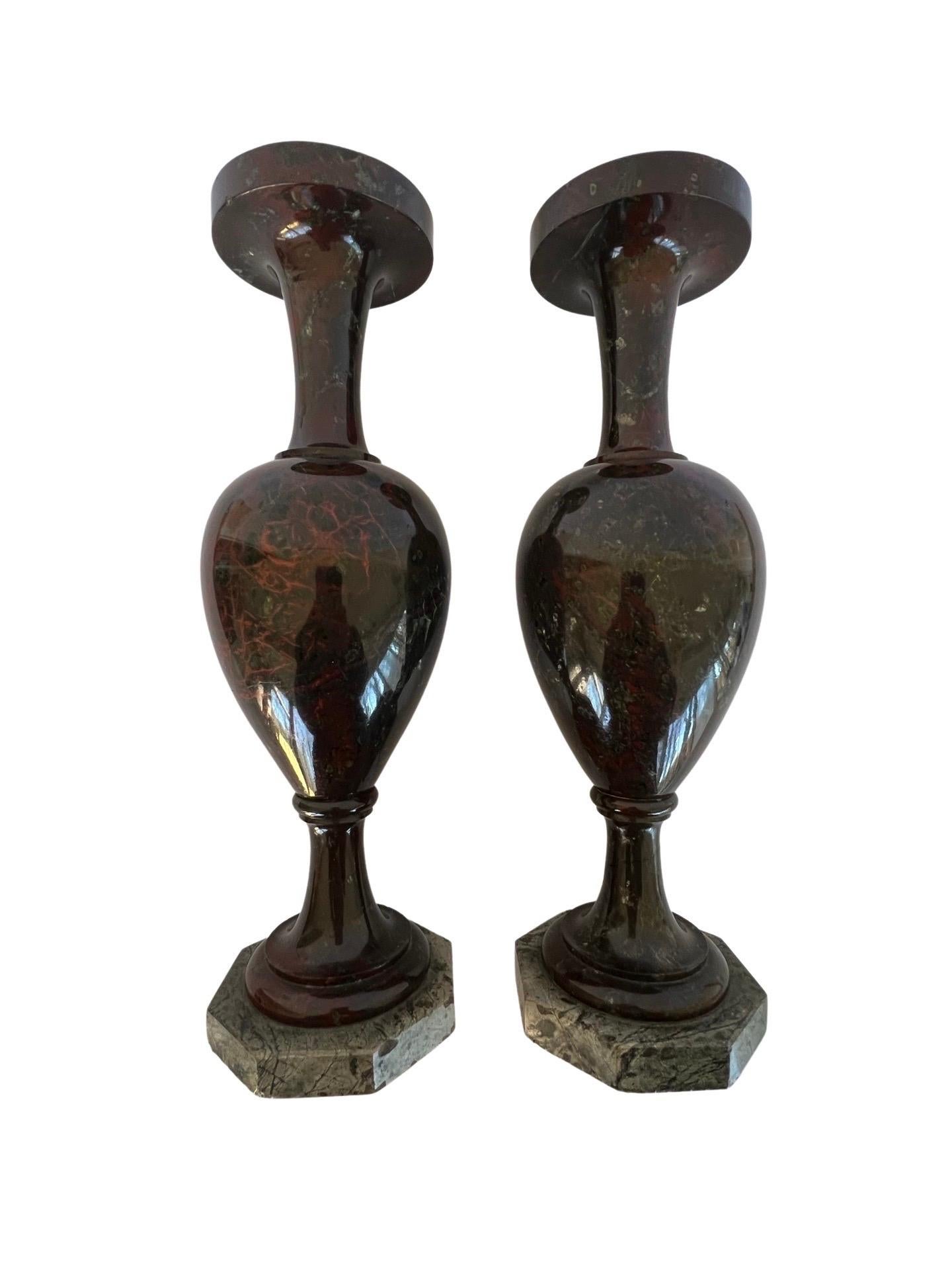 A pair of antique Cornwall vases carved from reddish brown jasper stone and date from the late nineteenth century. Each mounted to a marble base.