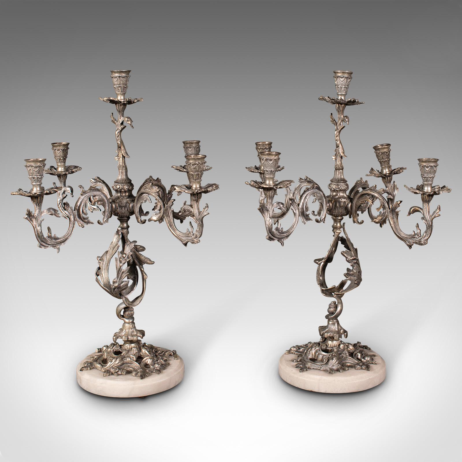 This is a pair of antique decorative candelabra. A French, silver nickel 4-branch centrepiece candlestick, dating to the Edwardian period, circa 1910.

Ornately decorated candelabra with appealing heft
Displaying a desirable aged patina