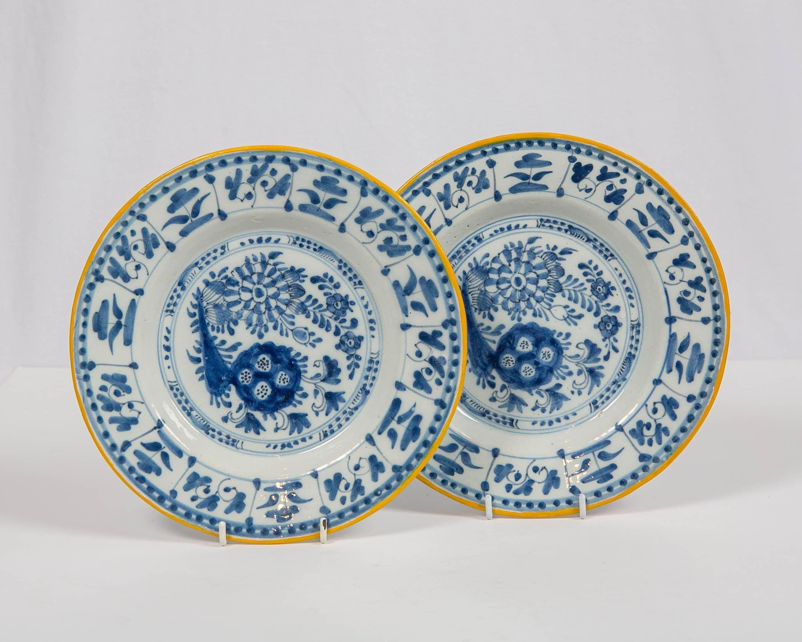 We are pleased to offer this pair of antique Dutch Delft blue and white plates which are hand painted with a lively scene of flowers, leaves and scrolling vines. The painter used both medium and deep cobalt blue to create the garden scene. The edge