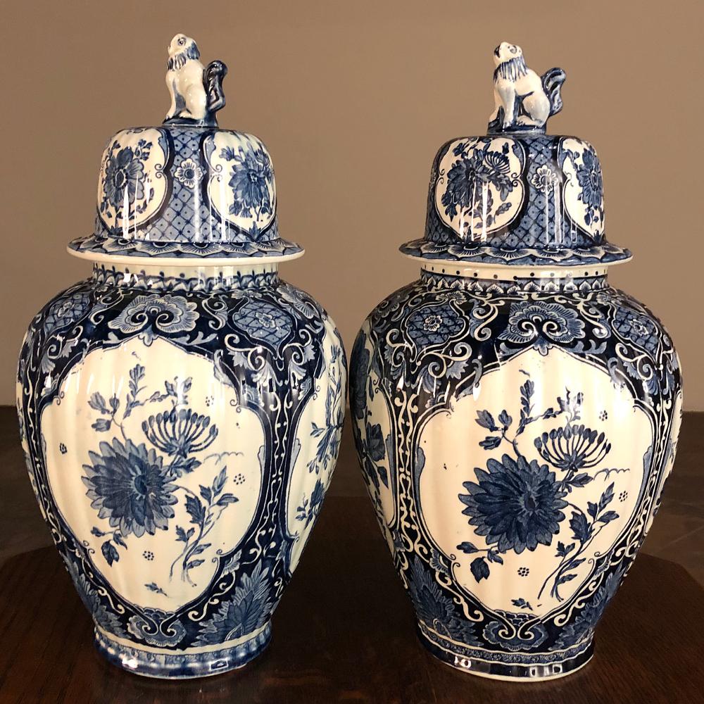 Pair antique Delft blue & white transferware lidded vases is a splendid example of Old World craftsmanship where Dutch ceramicists took advantage of the high demand for quality porcelain products from the Orient beginning as early as the 18th