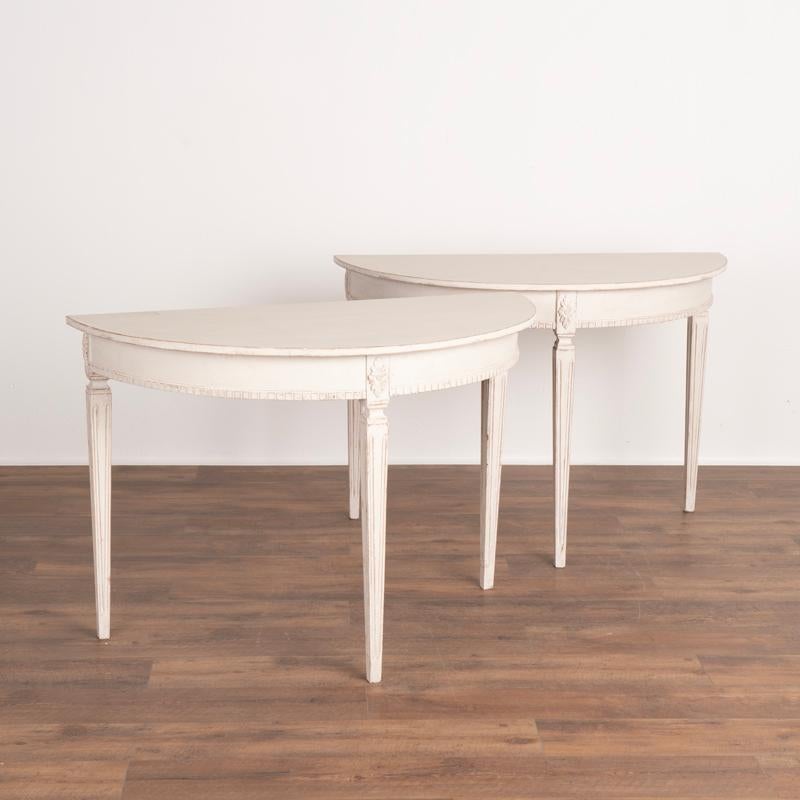 This lovely pair of antique demi lune tables are from Sweden. Note the perfectly tapered fluted legs and lovely skirt with dentil molding and floral accents adding a romantic touch to the pair. Both these side tables are finished with (newer) soft