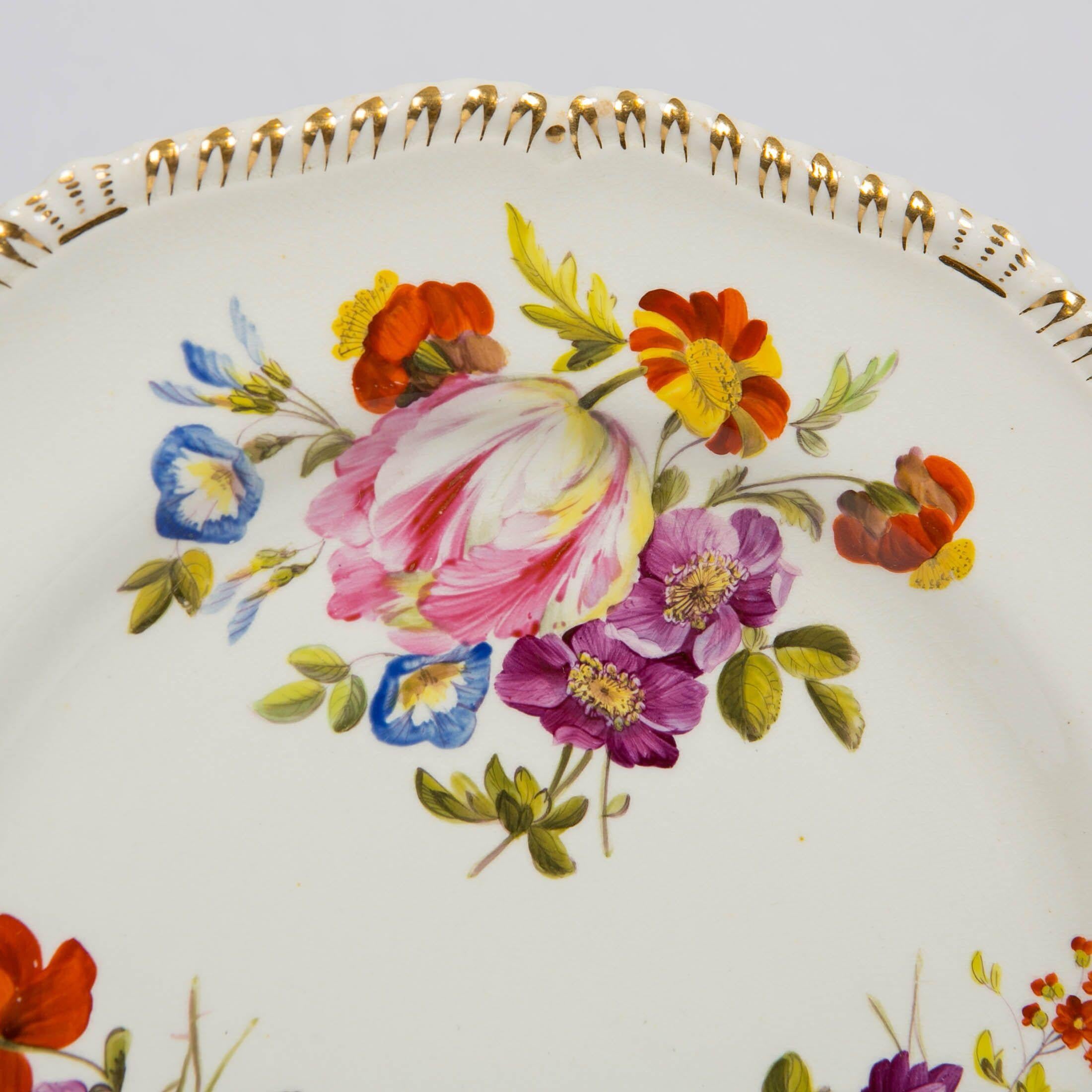 Cette paire d'assiettes en porcelaine de Derby a été peinte à la main, représentant de belles fleurs d'été dans des émaux polychromes brillants. Elles ont été peintes par l'éminent peintre de fleurs de Derby, Leonard Lead, vers 1825. Il a utilisé