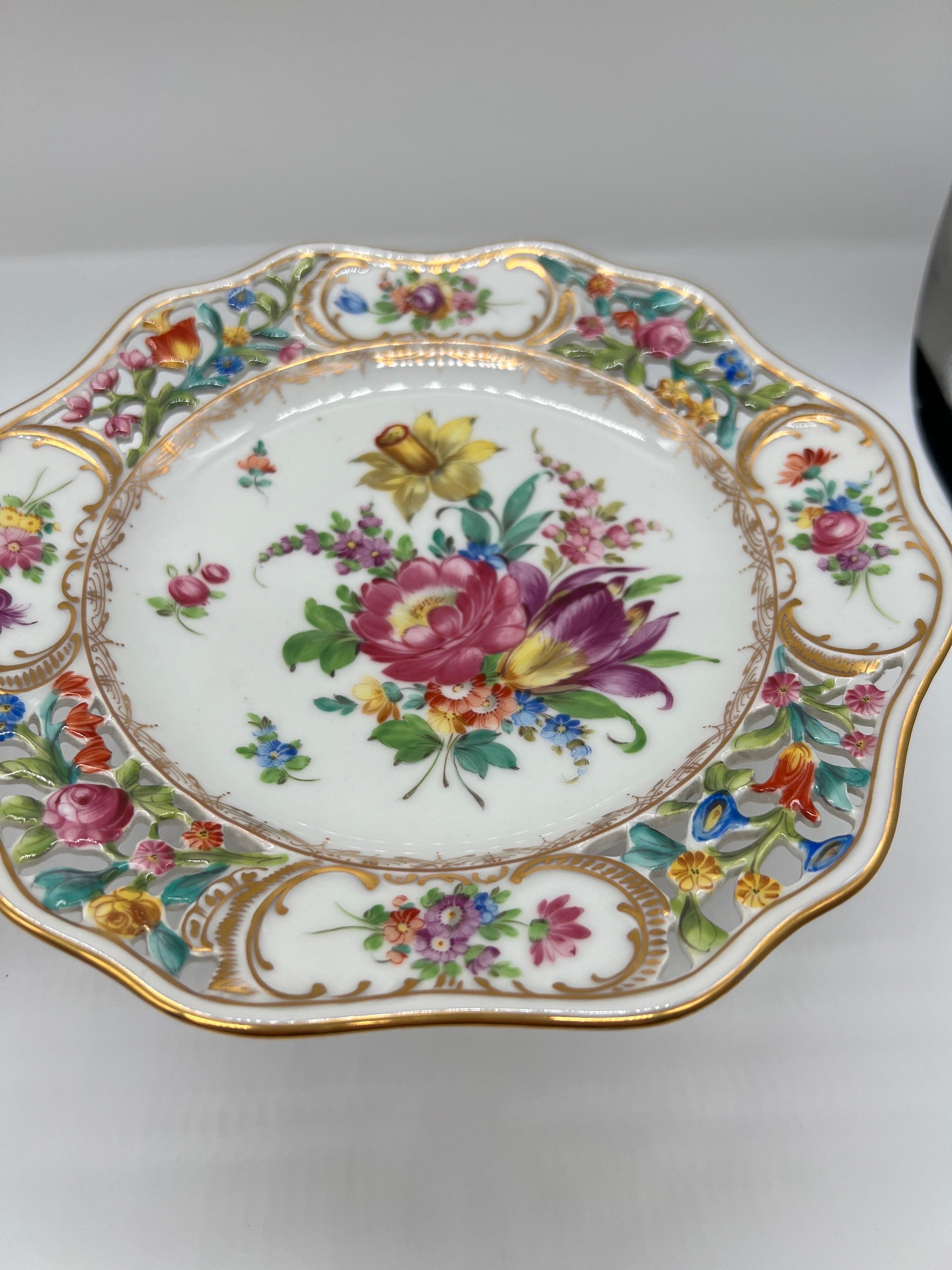 Dresden Germany, 20th century. 
A pair of antique compotes produced by the famous Dresden porcelain factory. Each compote is hand painted and decorated with a vast floral color array to the pierced edges and a finely decorated central foliate motif.