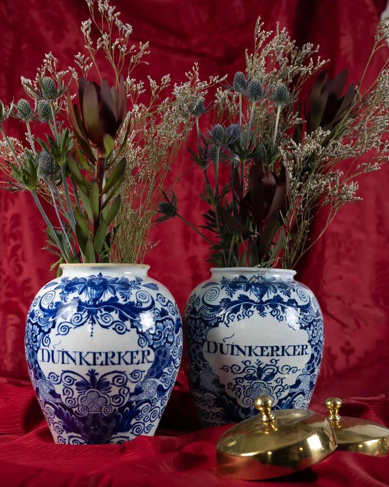 Questa coppia di antichi vasi da tabacco olandesi in bianco e blu di Delft, realizzati presso De Vergulde Bloempot a Delft intorno al 1770, è dipinta a mano con un bel fogliame che scorre, viti frondose e fiori.
Entrambi i vasi recano l'iscrizione