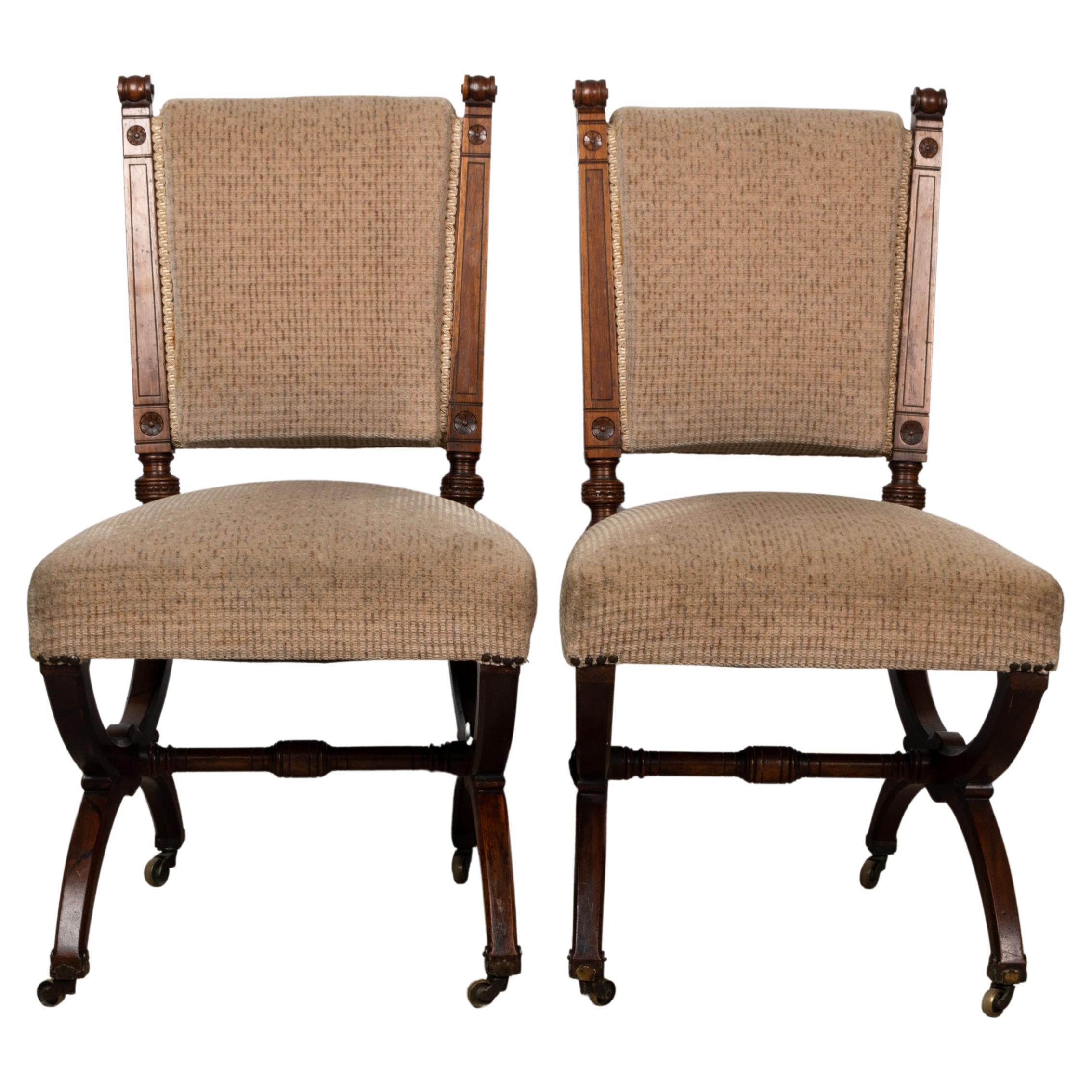 A pair of antique English Aesthetic movement X frame stretcher side chairs.

Attributed to Holland & Sons, each with a rosewood moulded frame with scrolled uprights, chamfered supports, raised on brass caps and castors, one stamped 'W. Bryson'.