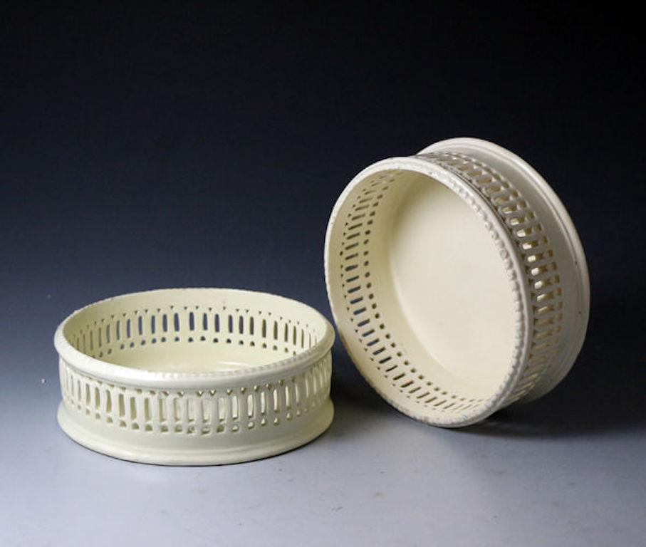 Dated circa 1780 Yorkshire or Staffordshire England

A pair of creamware pottery wine coasters with a reticulated arcaded border and a beaded rim. 
English and stylishly modeled in pottery from the similar pieces made in silver.

Dimensions:
