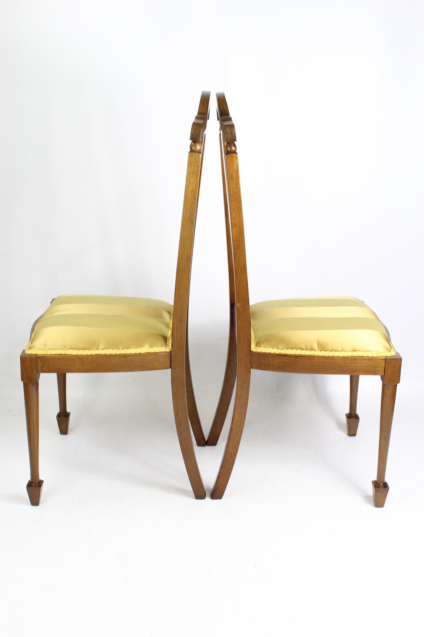 A stylish pair of antique Edwardian mahogany side chairs dating from circa 1910. With curved top rails and rail backs with attractive inlay and chequered banding to the central splats. They stand on tapered legs with spear feet. The seats have been