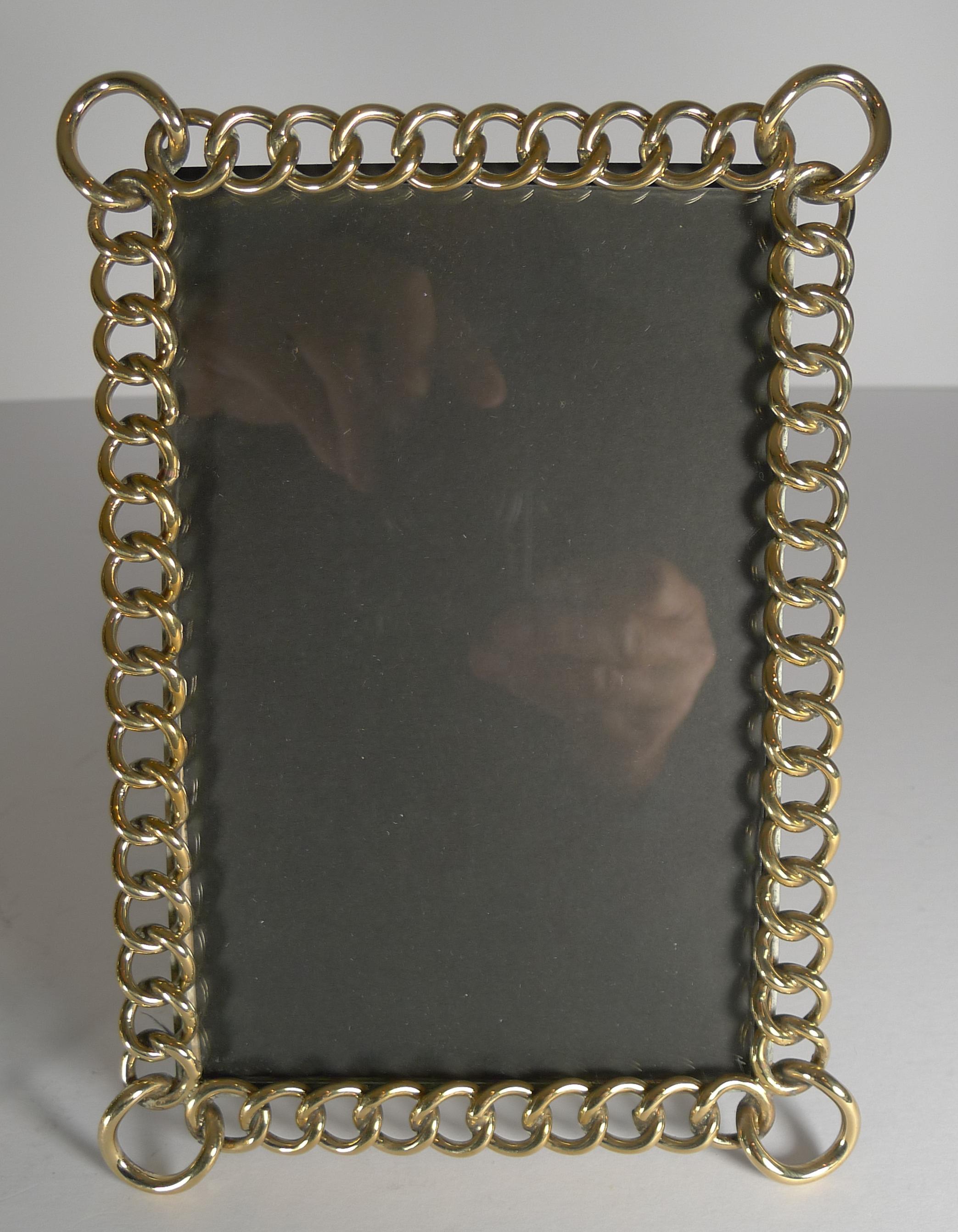 A handsome pair of late Victorian English photograph frames made from interlocking solid brass rings and standing on the original folding easel stands.

Victorian in era dating to circa 1890. Each measuring: 8