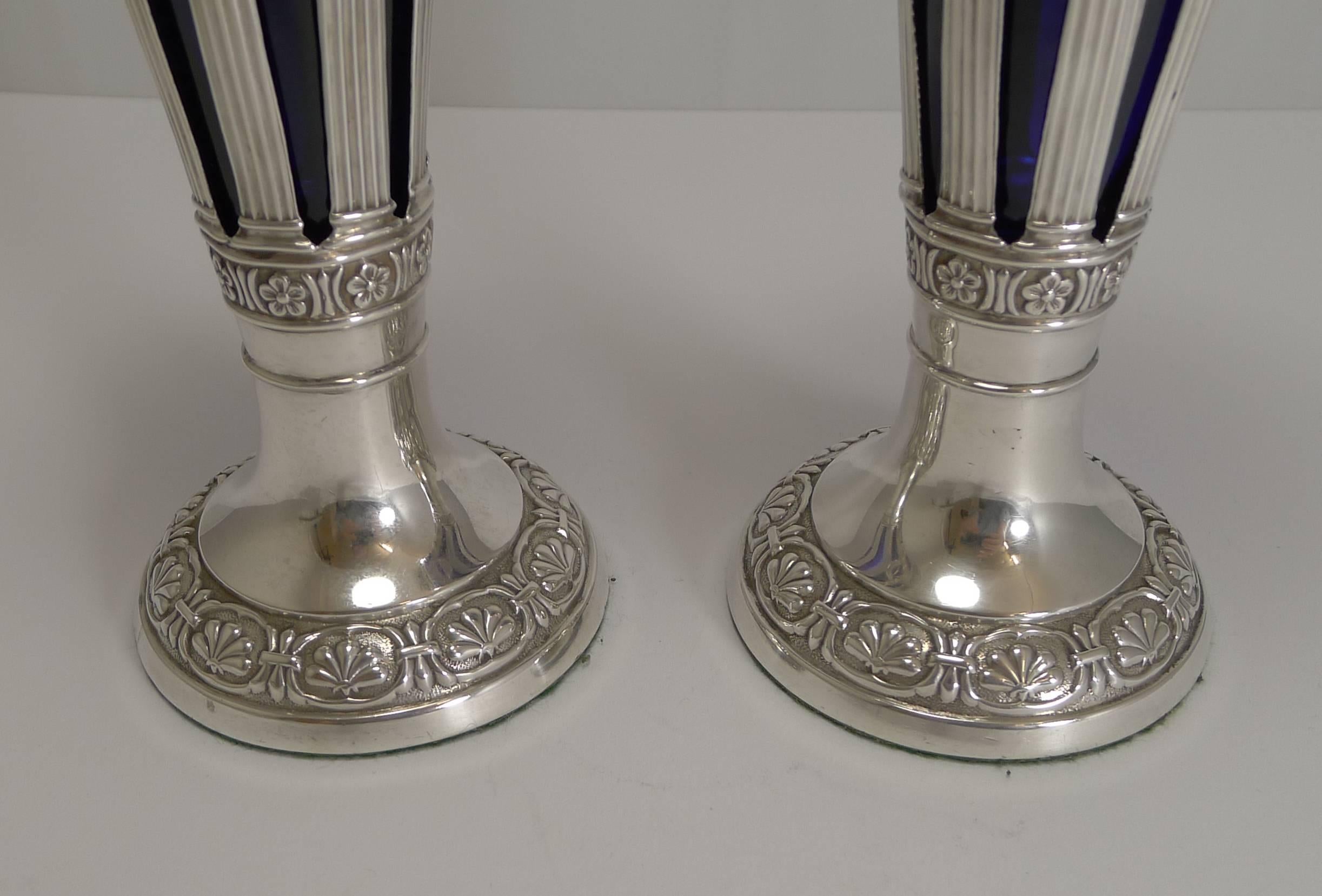 Une superbe paire de vases anglais édouardiens en argent sterling réticulé ou percé pour mettre en valeur les doublures amovibles en verre bleu Bristol. L'argenterie est décorée de motifs floraux et feuillus. Une guirlande florale continue, attachée