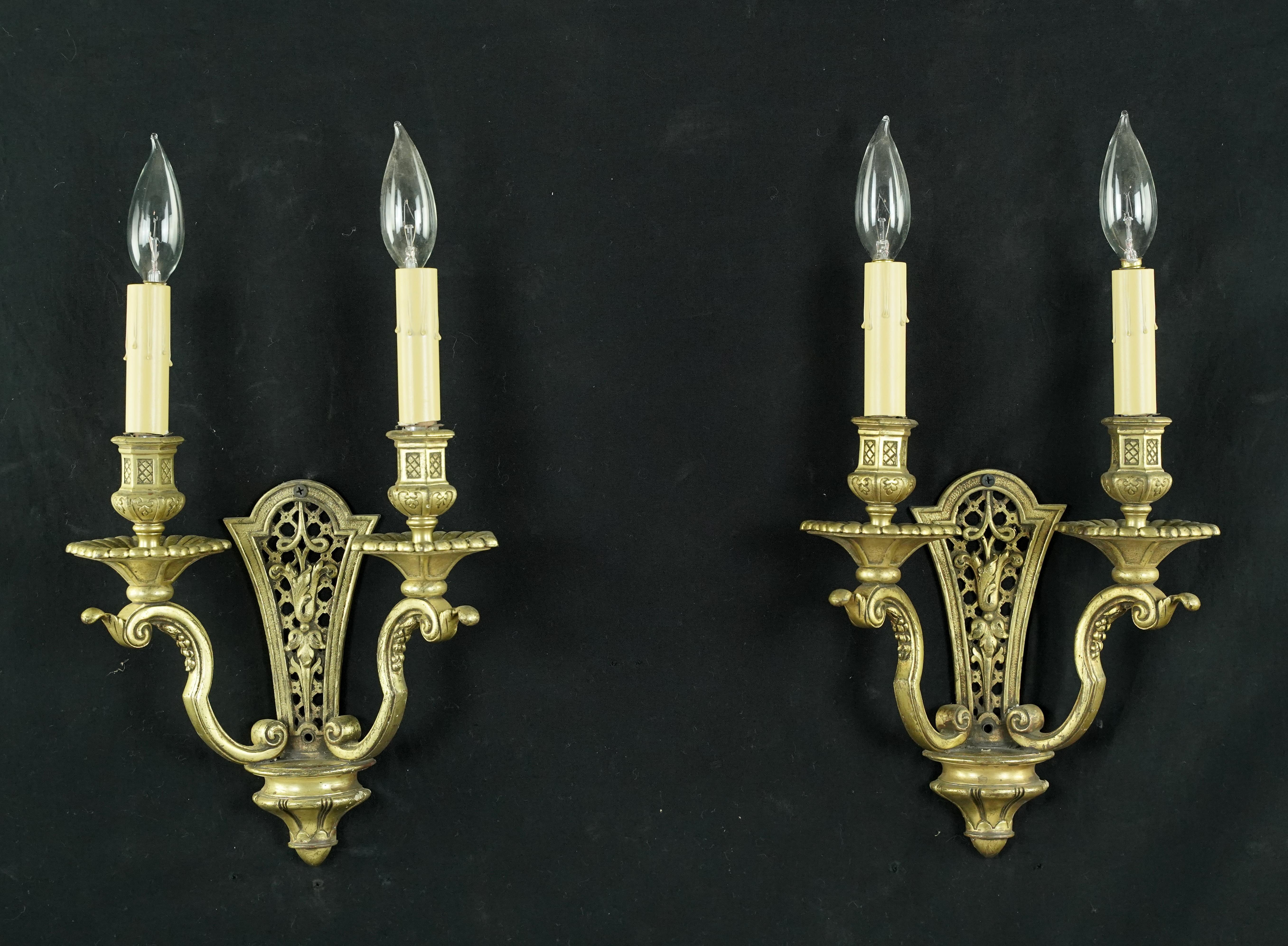 Antique French style wall sconces made of brass with tulip and lattice detailed frames. The price includes restoration of cleaning and rewiring. Each sconce requires two E-12 candelabra light bulbs. Priced as a pair. Cleaned and restored. Please