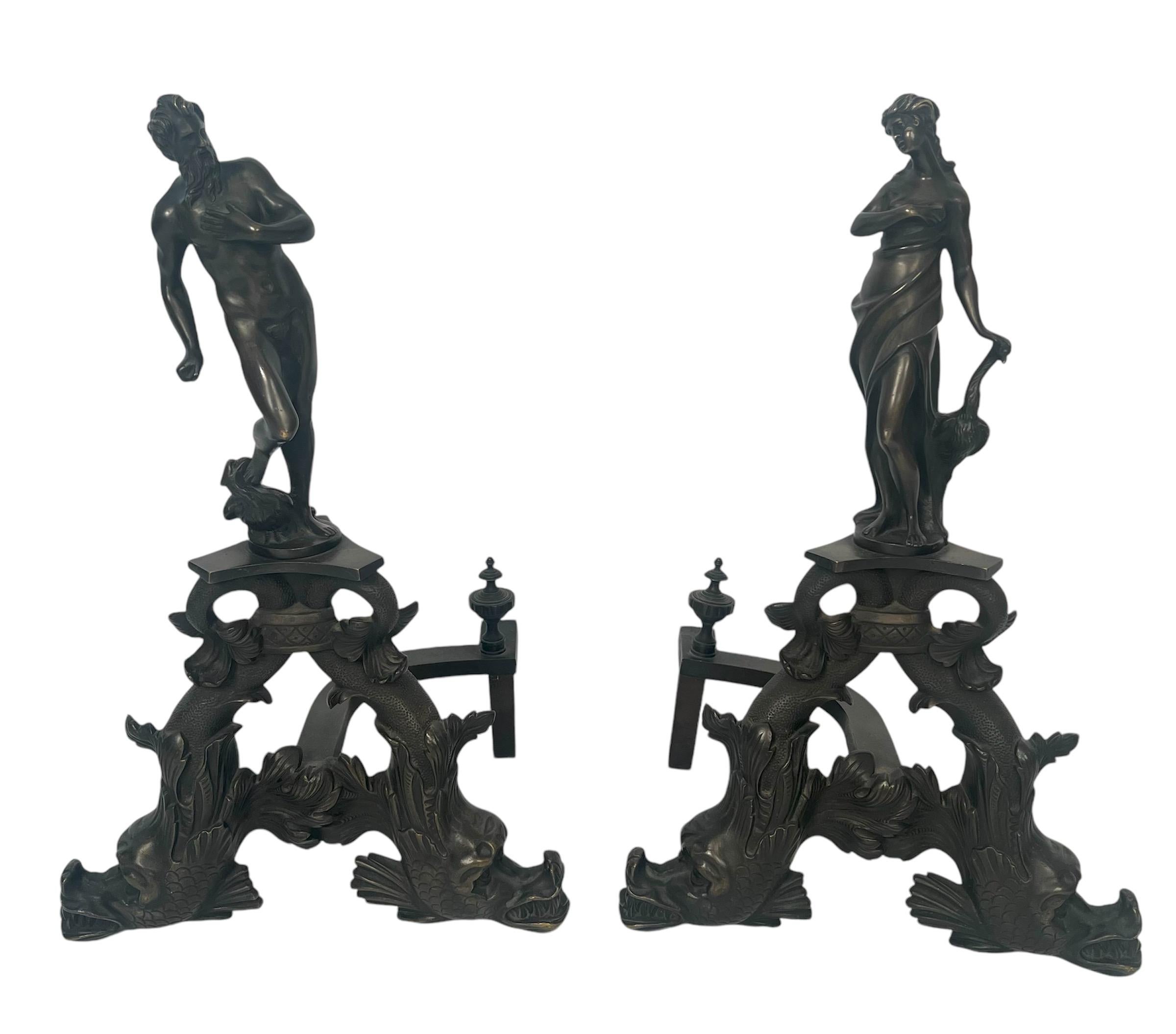 Une impressionnante paire de chenets anciens en bronze figuratif français du 19ème siècle.  Des dauphins à la base soutiennent une urne surmontée d'une femme et d'un homme.  L'homme et la femme ont un oiseau, peut-être un phénix, à leurs côtés. Très