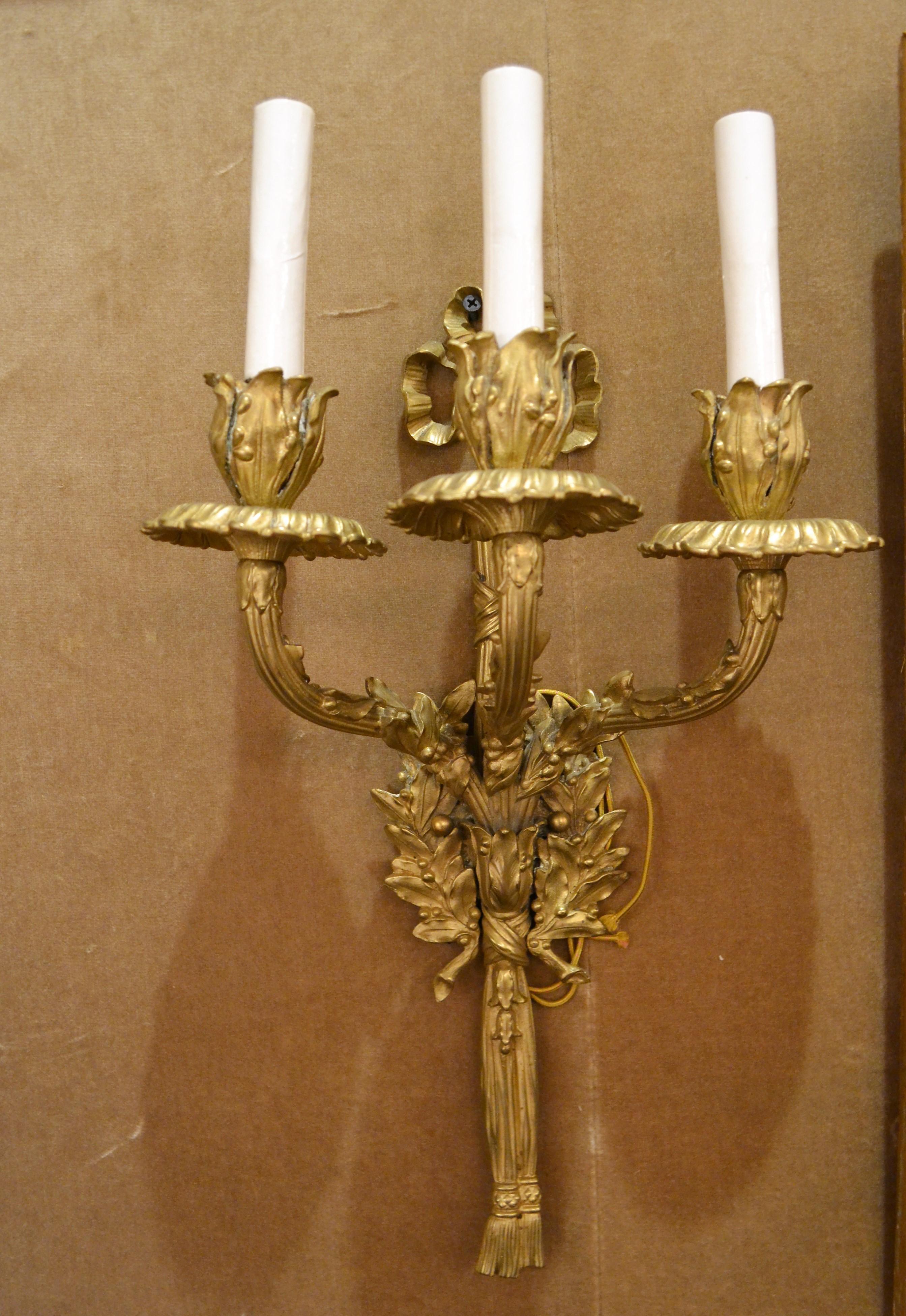 A pair of nicely crafted three- light French sconces with the pretty bow element at the top.