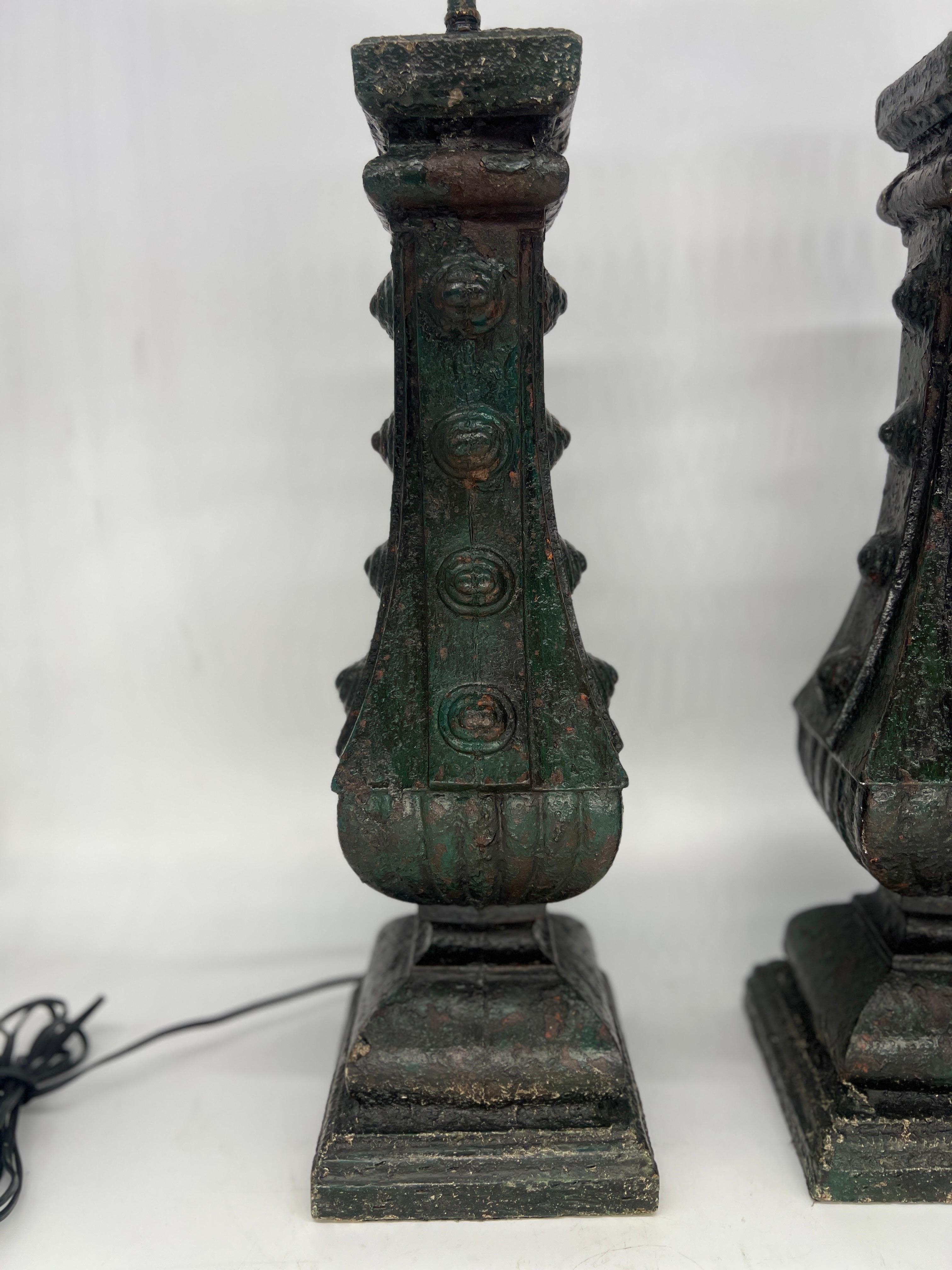 French, 19th century or earlier. 

Each lamp features an authentic cast iron architectural fragment, seamlessly transformed into a lamp base with the utmost care and craftsmanship. The cast iron, with its aged patina and period green paint, bears