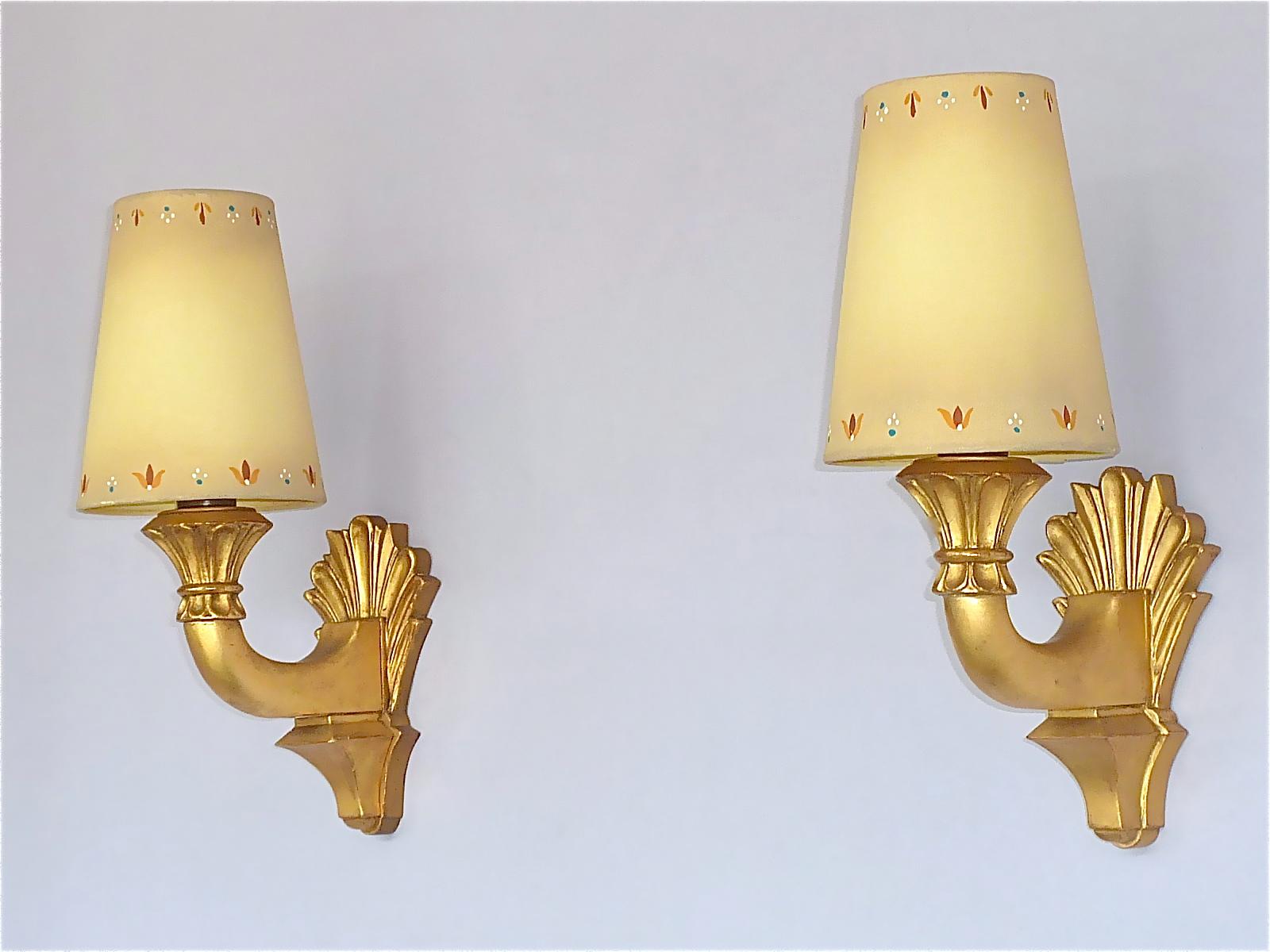 Pair of antique Art Deco gilt wood wall sconces, France or Italy around 1900 to 1920. The beautiful hand-carved gilt wood on partly visible red ground appliques have original brass porcelain fittings for one E27 standard screw bulb to illuminate.