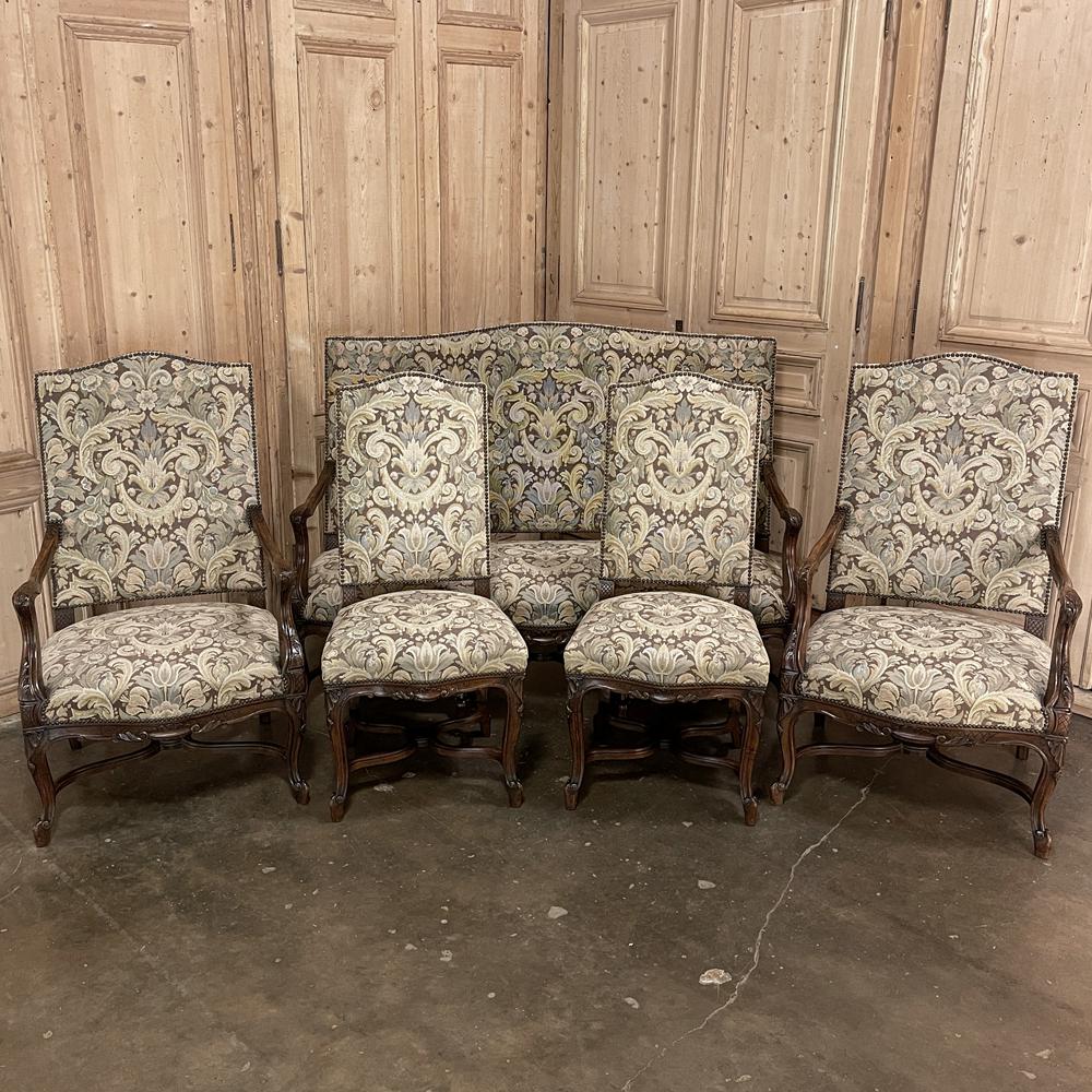 Pair Antique French Louis XV armchairs with Tapestry Upholstery was sculpted from fine walnut, and features exquisitely formed frameworks with subtly arched seatback crowns, gracefully scrolled armrests, and undulating aprons supported by eight