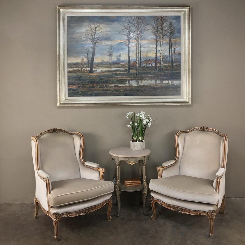 Pair of antique French Louis XV bergeres, armchairs feature timeless Rococo styling with intricately scrolled, naturalistic form to the frameworks accentuated with floral and foliate relief from the arched crown to the contoured apron and cabriole