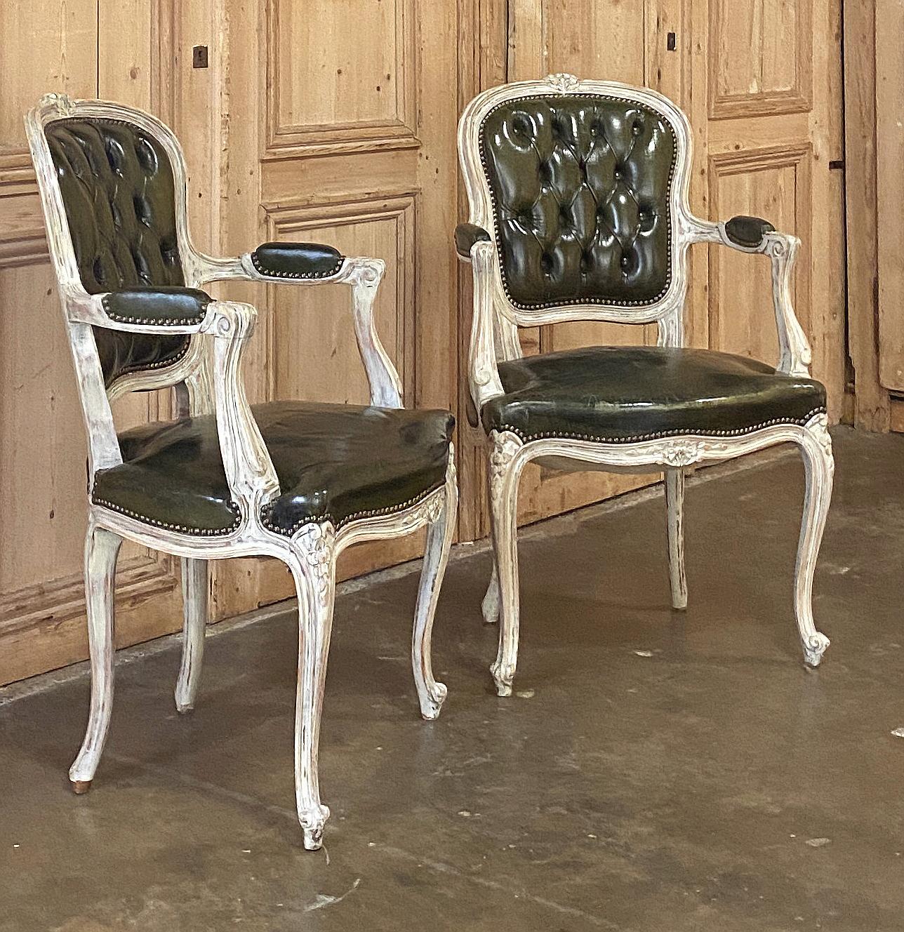 Pair Antique French Louis XV Painted Armchairs with Leather represent the epitome of the style, with gracefully contoured frameworks emulating the forms of nature, surrounding the ergonomically tufted seatback and generous seat.  Scrolled armrest