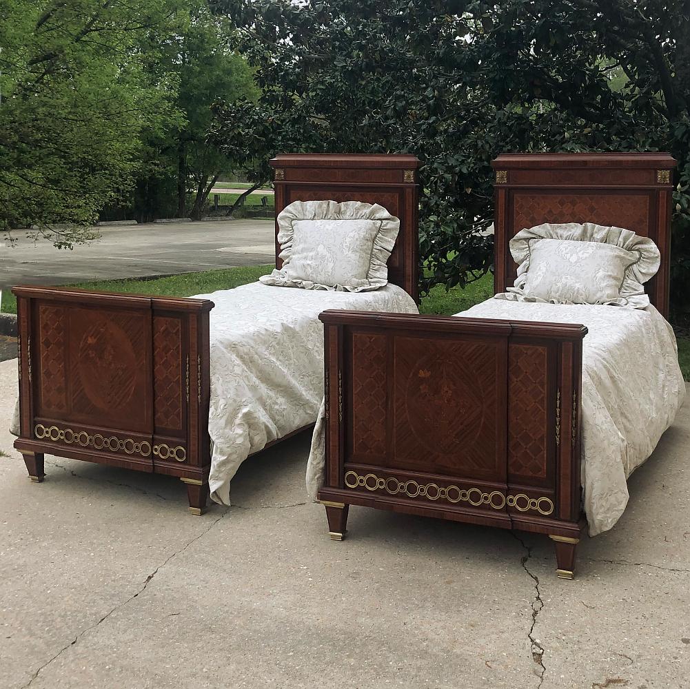Pair of antique French Louis XVI mahogany marquetry twin beds with bronze ormolu are masterpieces of the furniture maker's art! Meticulously crafted in Paris from exotic imported mahogany, each features amazingly detailed marquetry on the headboard