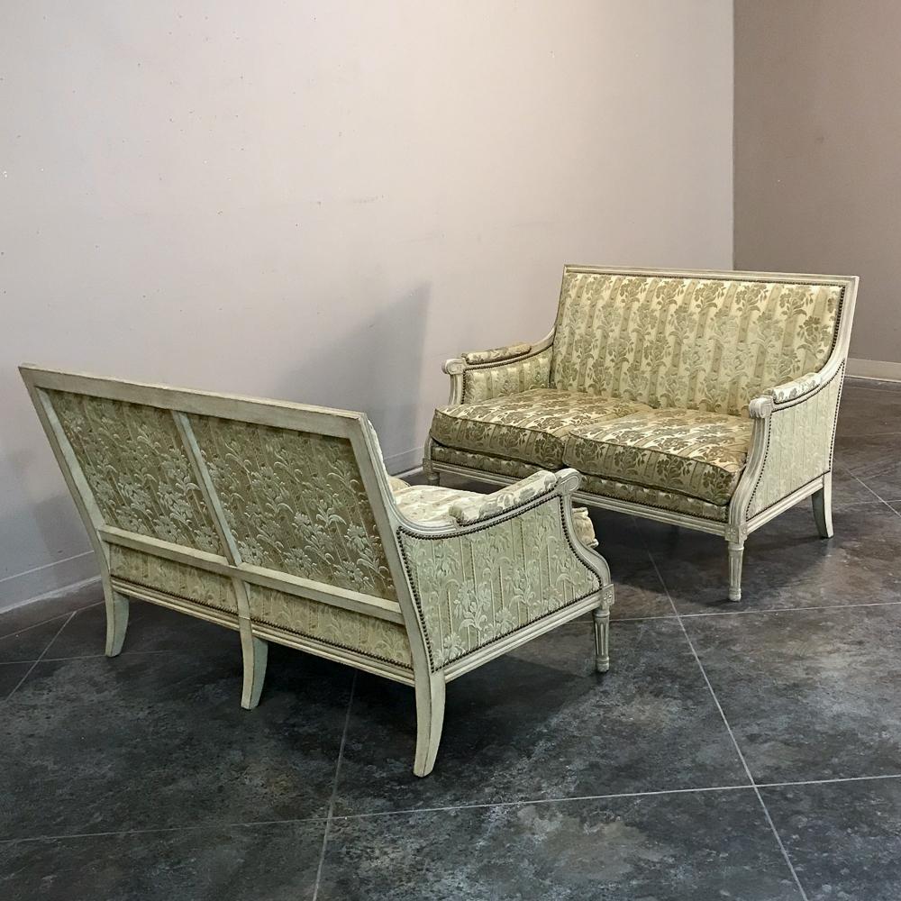 Pair of antique French Louis XVI painted sofas is a rare find indeed! Classical styling includes beautifully hand carved frames with comfortably bergere-style armrests. Detailed molding pervades the design, accentuated by the patinaed painted