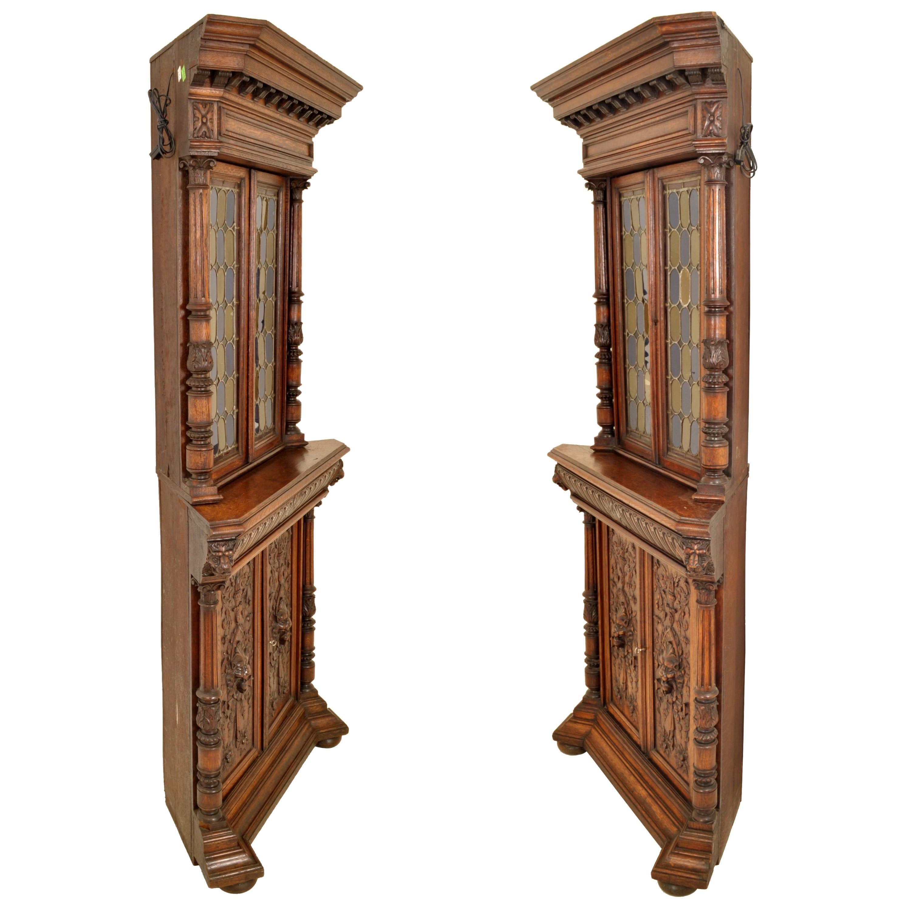 A magnificent & rare pair of antique French Renaissance Revival carved oak and leaded stained glass corner cabinets, circa 1880.
Each cabinet comprises two sections having a stepped cornice with corbel bracket supports to the top, the top section