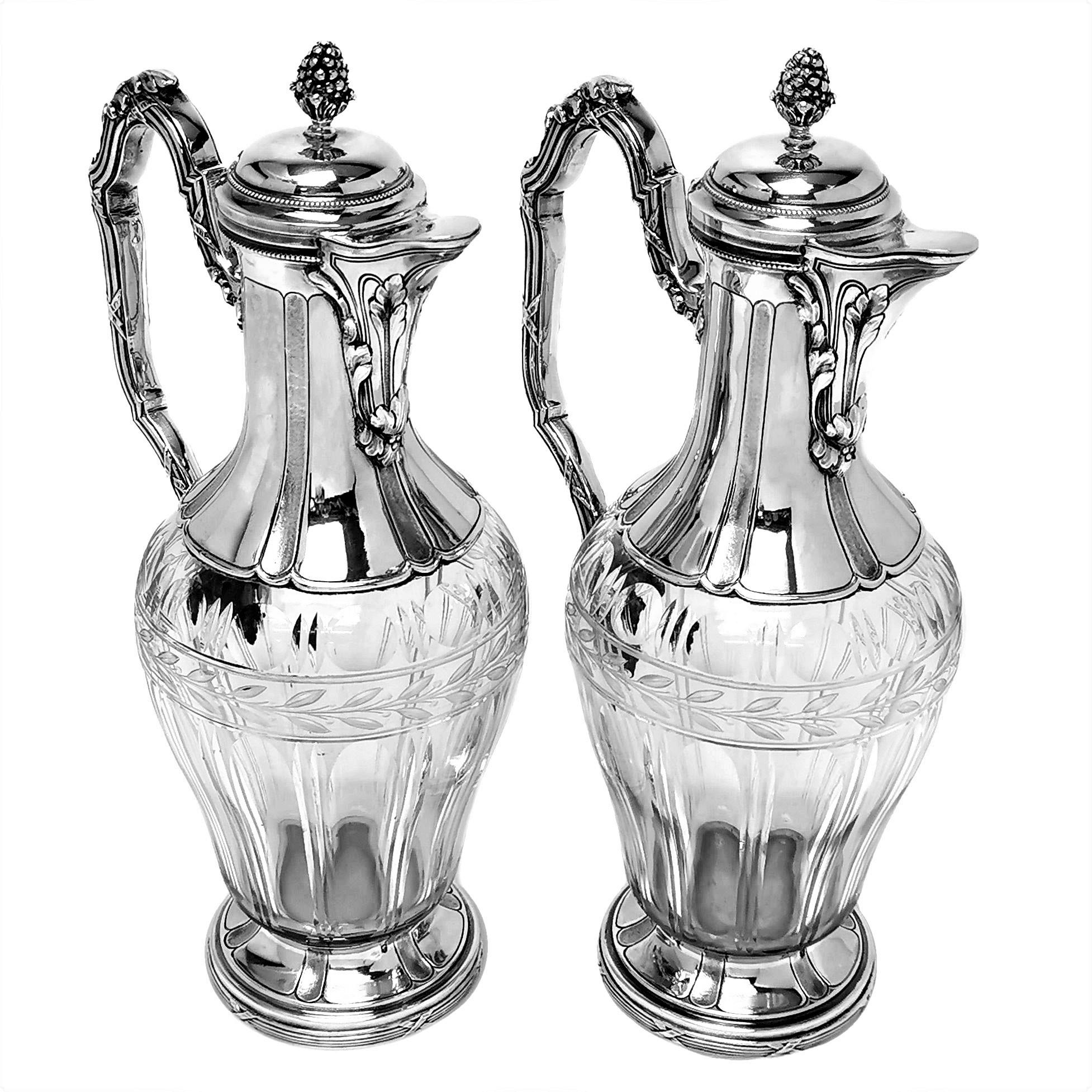 A pair of elegant Antique French silver & glass Claret Jugs. The bodies of these Wine Jugs feature lovely cut glass patterns which complement the patterning on the foot and neck of the Wine Jugs. The foot and handle of the Ewers are embellished with