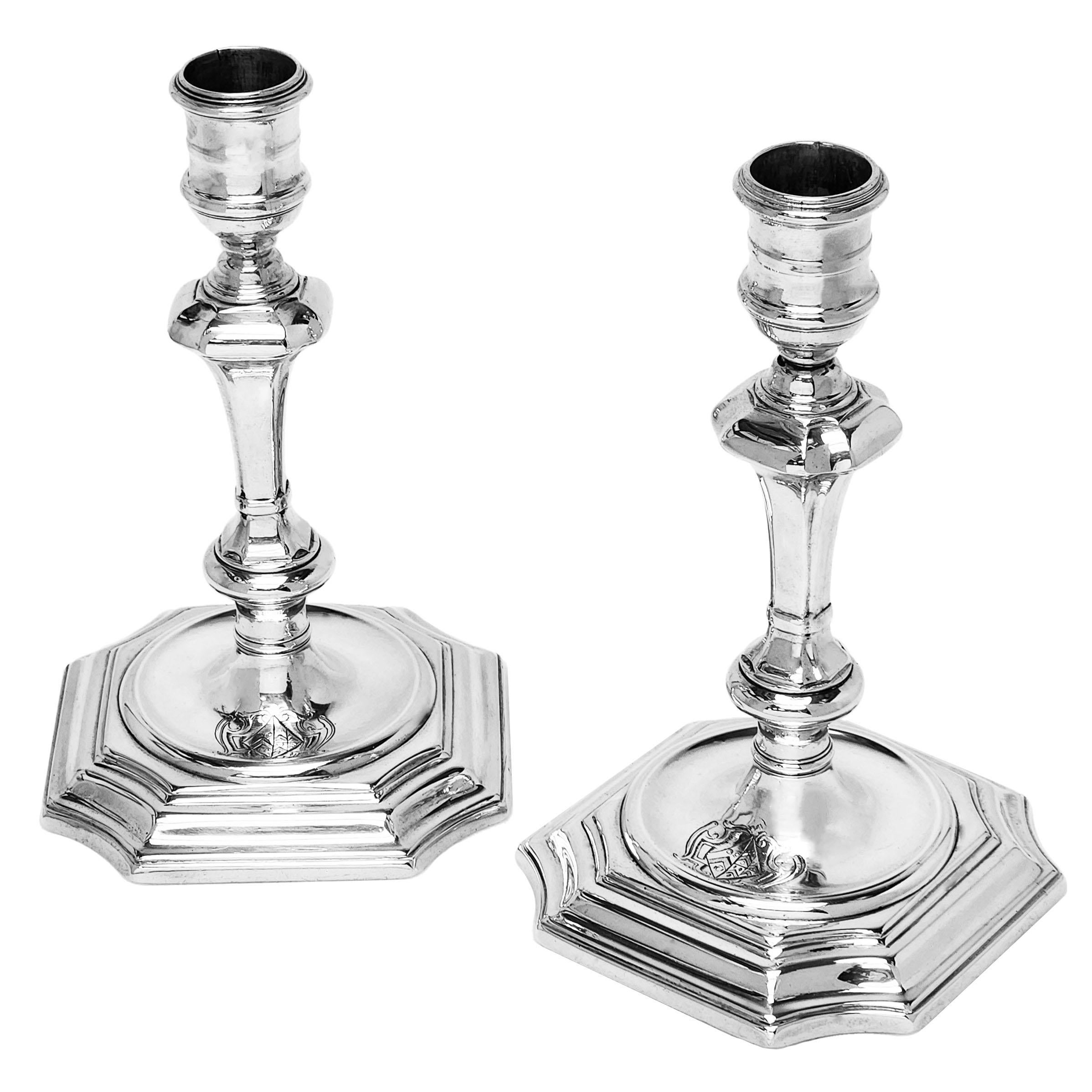 Un'elegante coppia di candelieri classici in argento sterling fuso di Giorgio I. Questi candelabri d'argento dell'inizio del periodo georgiano hanno basi quadrate sagomate con angoli tagliati concavi, pozzetti incassati e colonne quadrate con