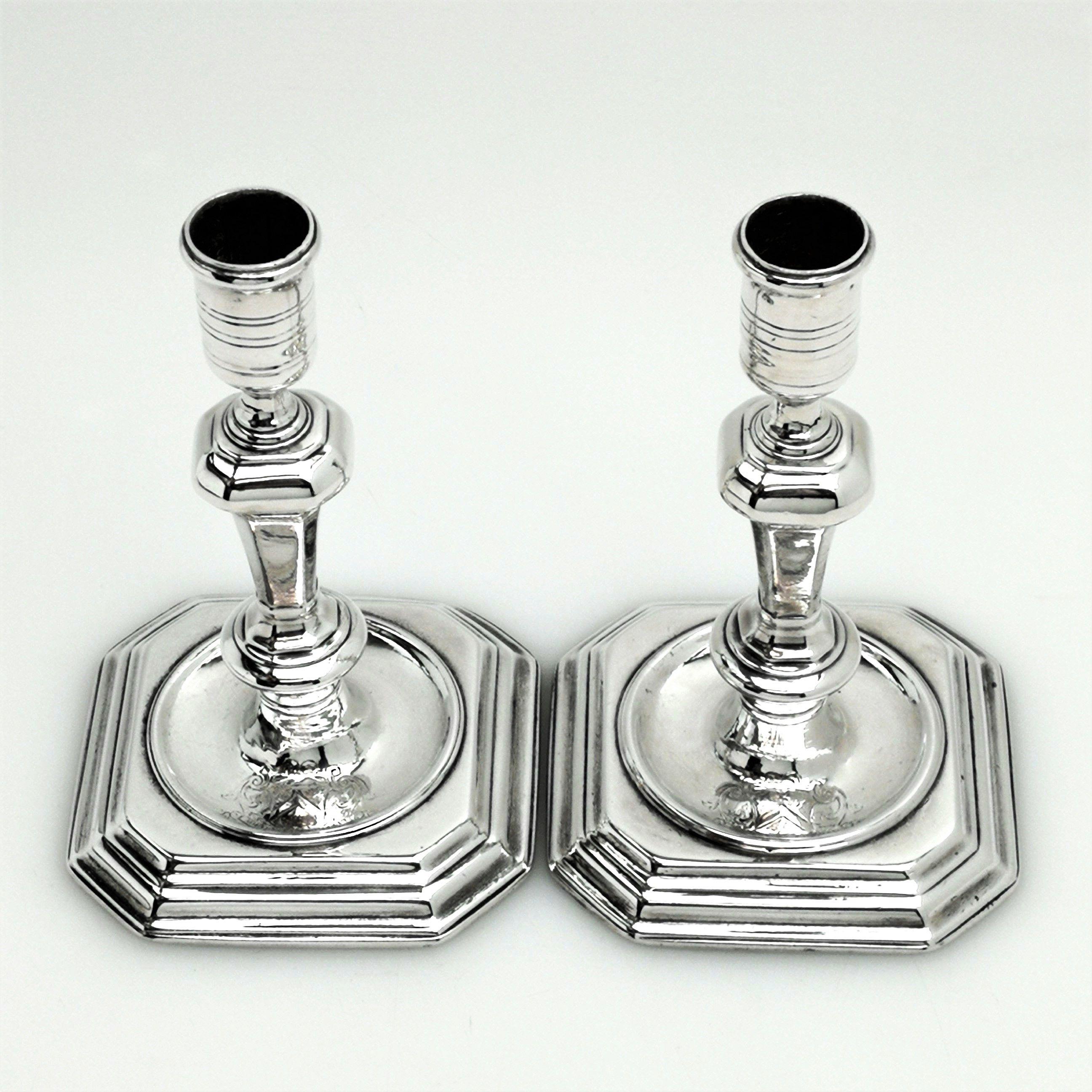A magnificent pair of Britannia standard solid Silver George I silver candlesticks. These Georgian cast silver candlesticks have square bases with cut corners, mirrored in the octagonal knopped column. The candlesticks have sunken well bases and