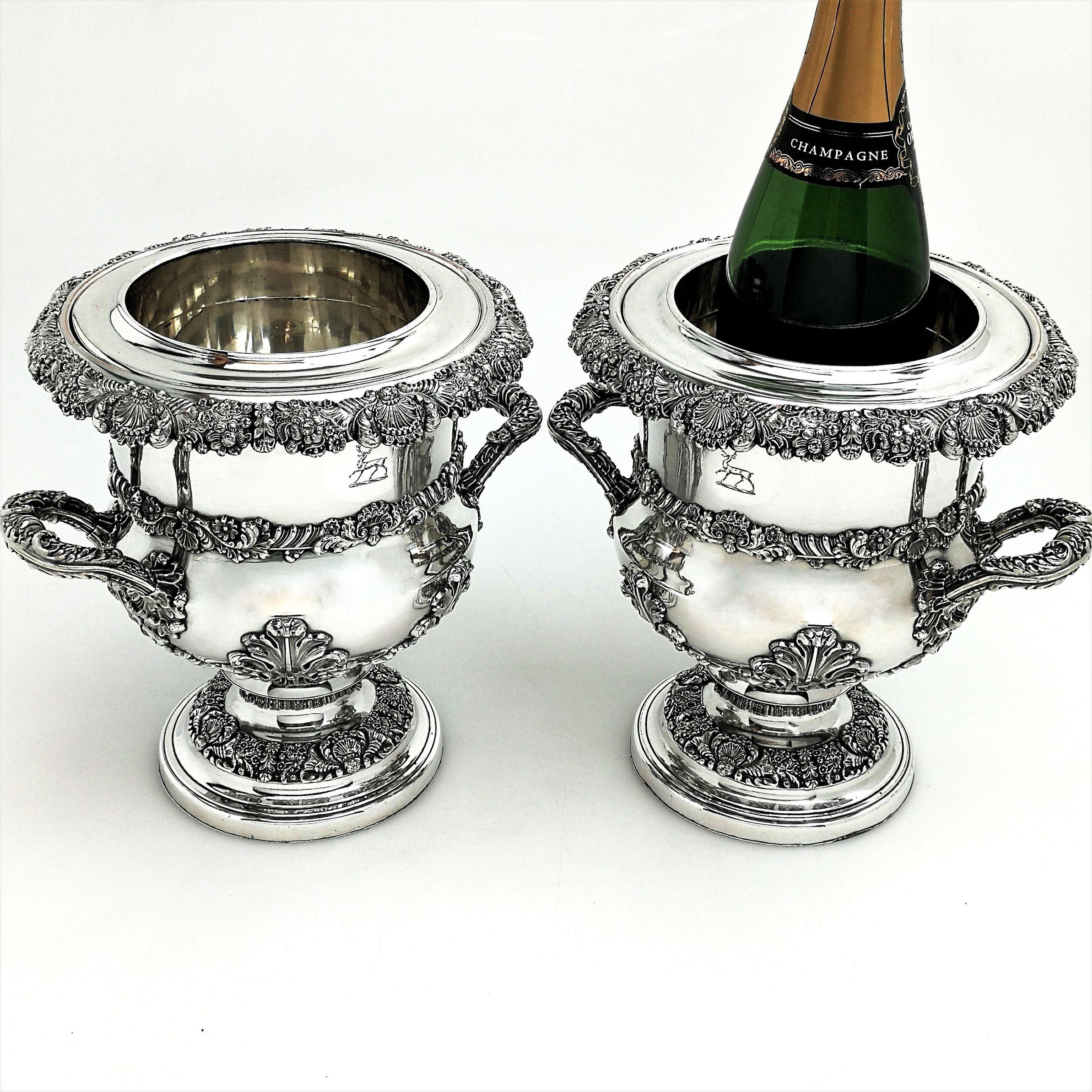 An impressive pair of antique Georgian old Sheffield silver plate wine coolers. These George IV Sheffield plated champagne coolers have ornate floral, shell and scroll bands and each has a pair of beautiful handles. The buckets each stand on a