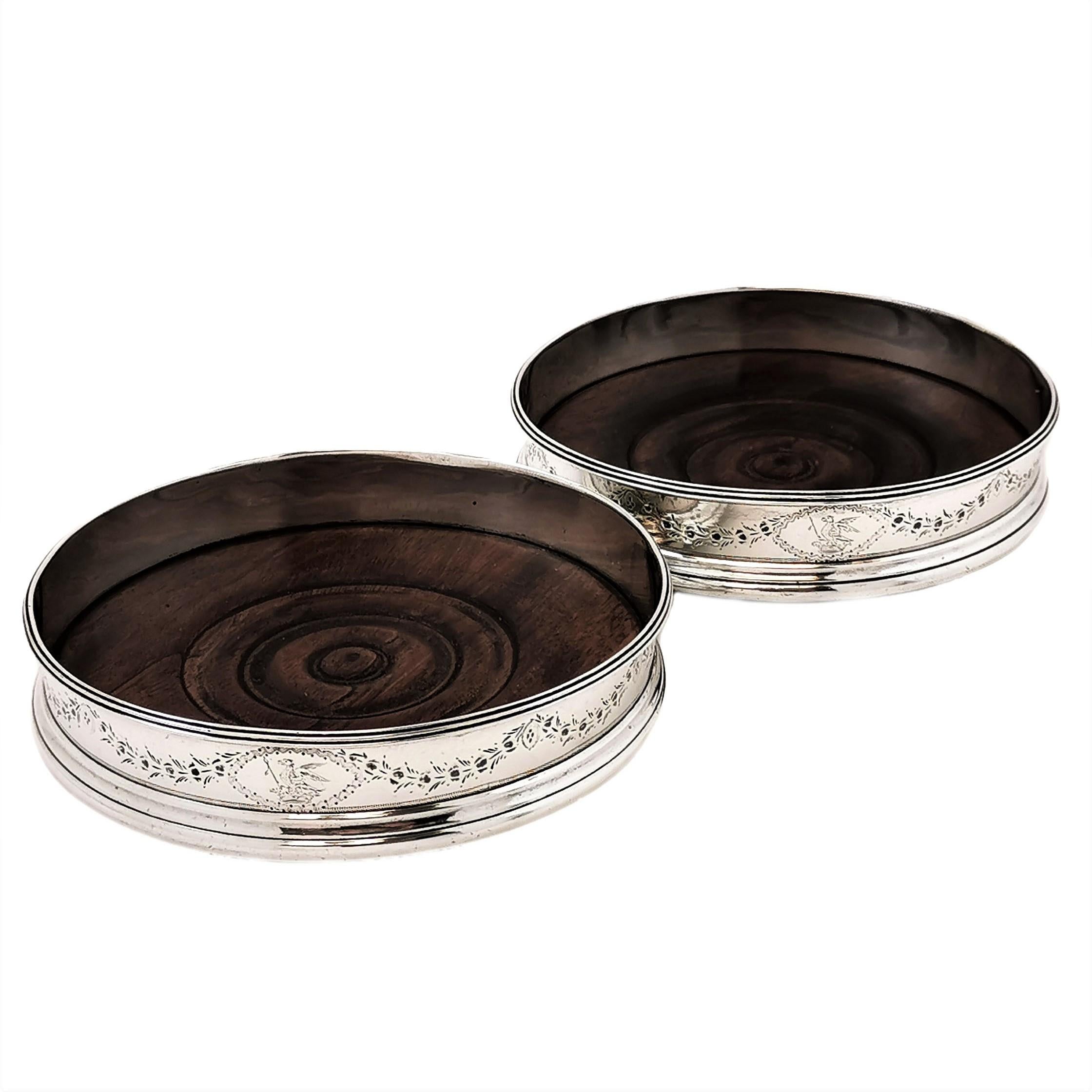 A pair of lovely Antique George III sterling Silver Wine Coasters with wooden bases. The Solid Silver sides of the Coasters each have delicate engraved floral band with a small cartouche surrounding an engraved crest.

Made in London in 1786 by