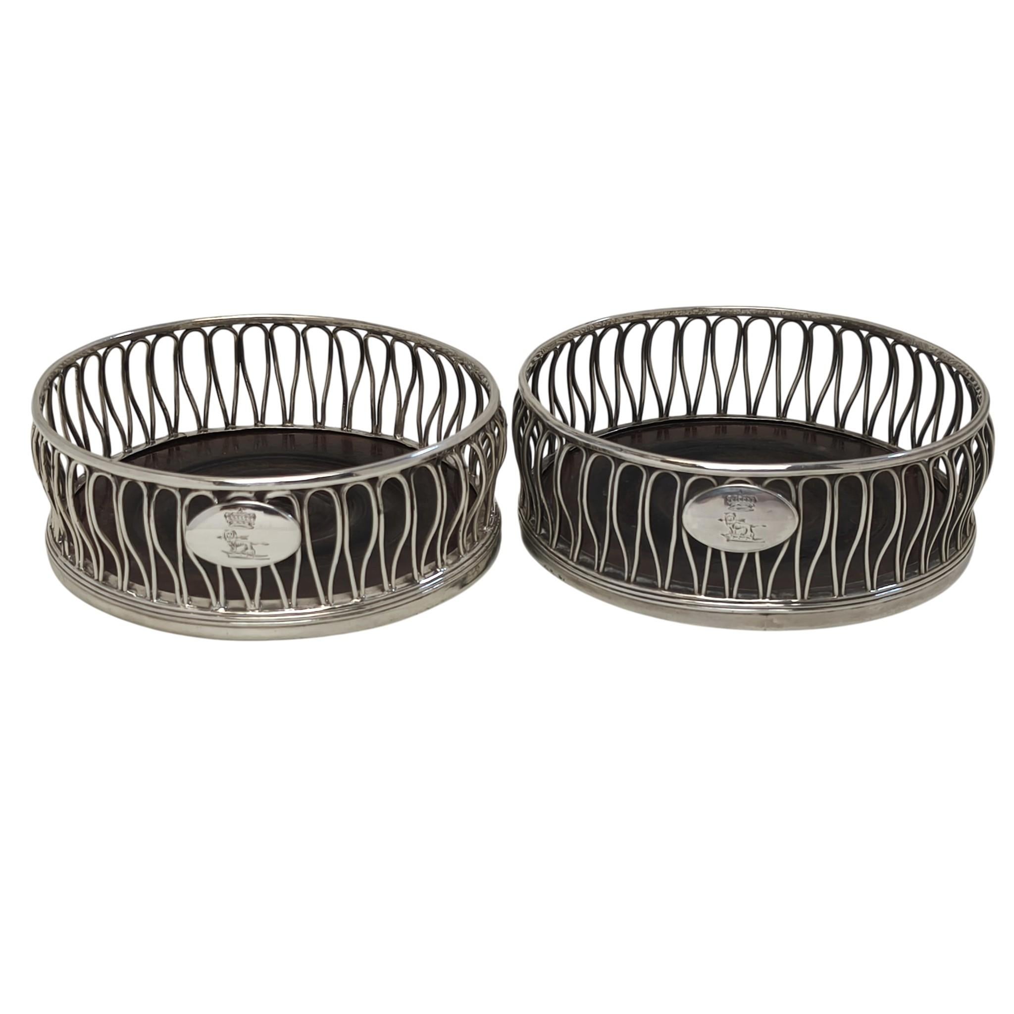 Una coppia di splendidi sottobicchieri per bottiglie di vino in argento sterling di Giorgio III con un elegante motivo a filo ripetuto sui lati. Ogni sottobicchiere ha un piccolo cartiglio ovale con uno stemma inciso al centro. La base di ogni