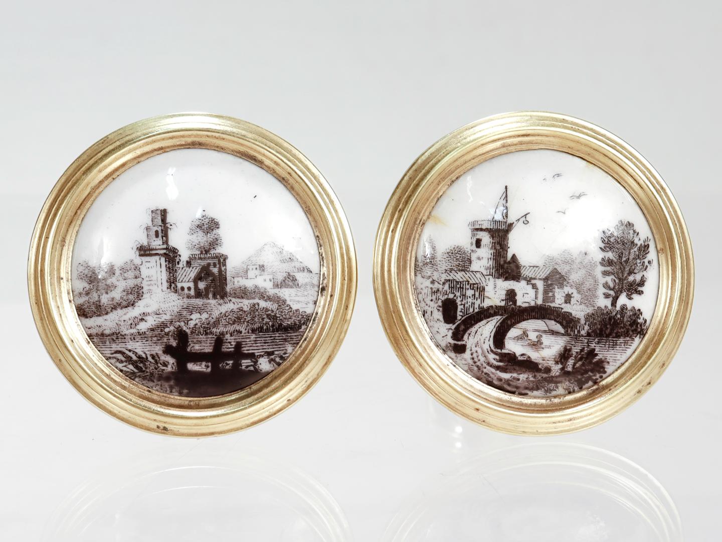 A fine pair of antique Georgian curtain tiebacks.

In turned brass and tin and set with Battersea or Bilston enamel plaques to the front threaded steel shafts to the reverse.

The Battersea plaques decorated with black decoration depicting landscape