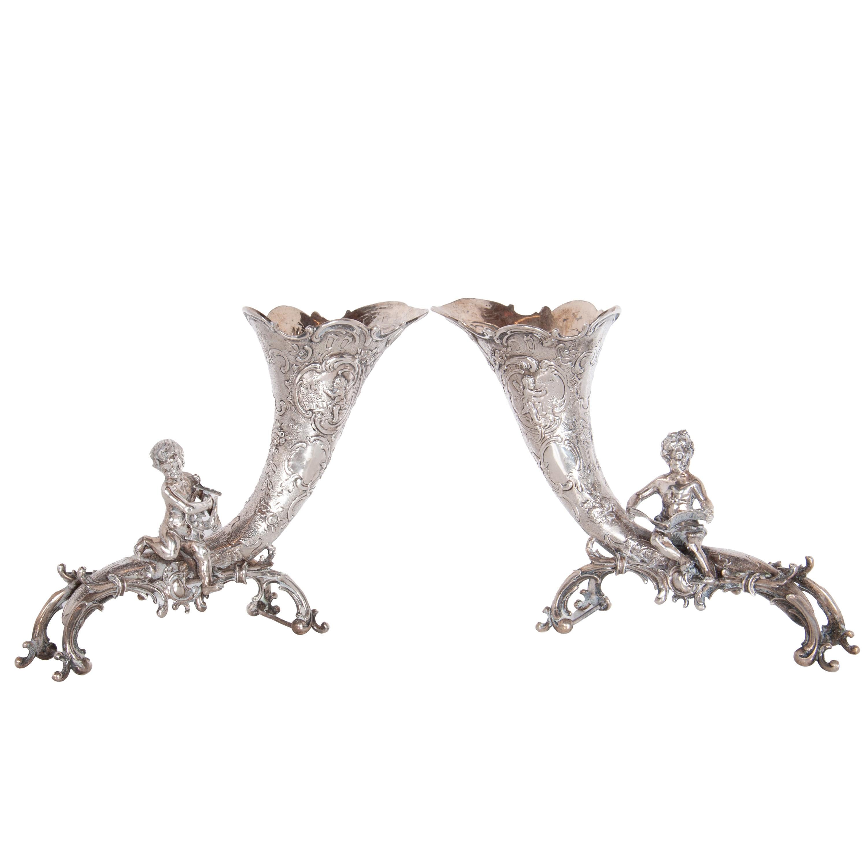 Una bella coppia di antichi vasi tedeschi a cornucopia in argento con cherubini, Hanau, circa 1890.

I vasi sono probabilmente opera di Friedrich Reusswig, un argentiere di Hanau, in Germania, 
Realizzato in argento .800 e in stile rococò, ogni vaso