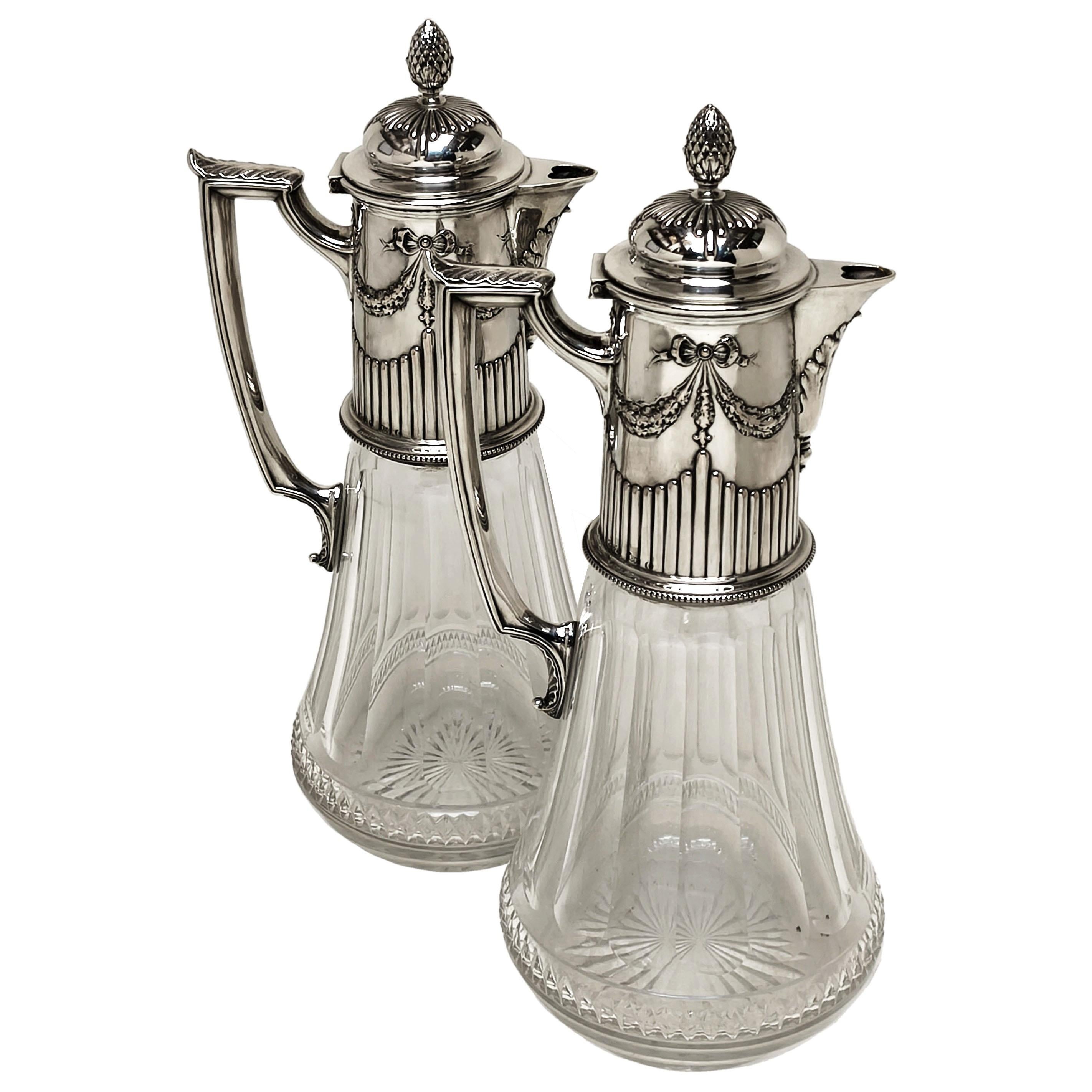 Une paire de jolies cruches en argent allemand ancien et en verre taillé. Chaque cruche a un corps en verre clair taillé avec un col, un couvercle et une poignée en argent ciselé. Le col de la cruche est orné d'une délicate ciselure composée d'une
