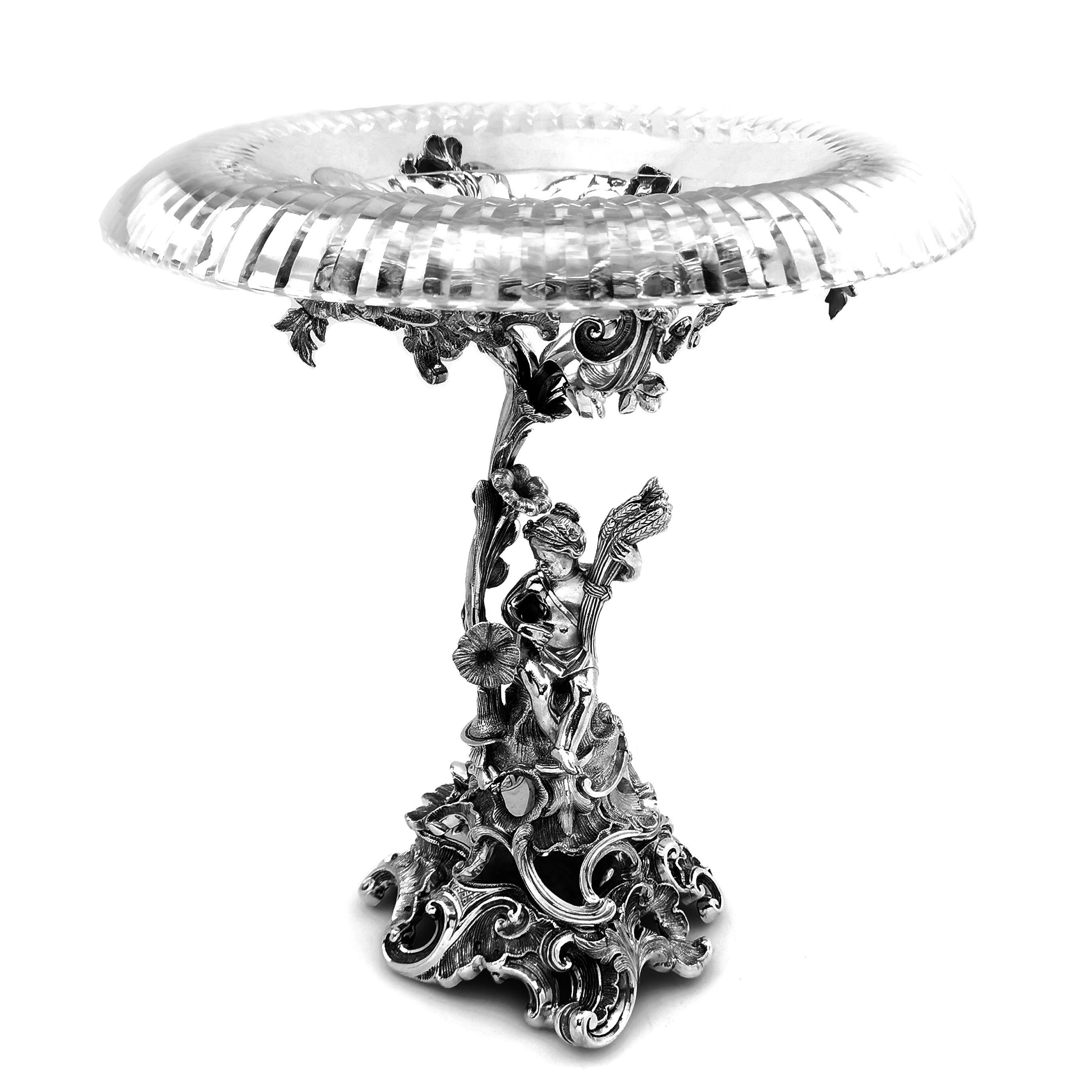 A magnificent pair of Antique German solid Silver and cut Glass Comports. These Comports have beautiful solid silver bases of a floral and scroll designs, each with a figure included in the central column. The column opens up into a floral stylised