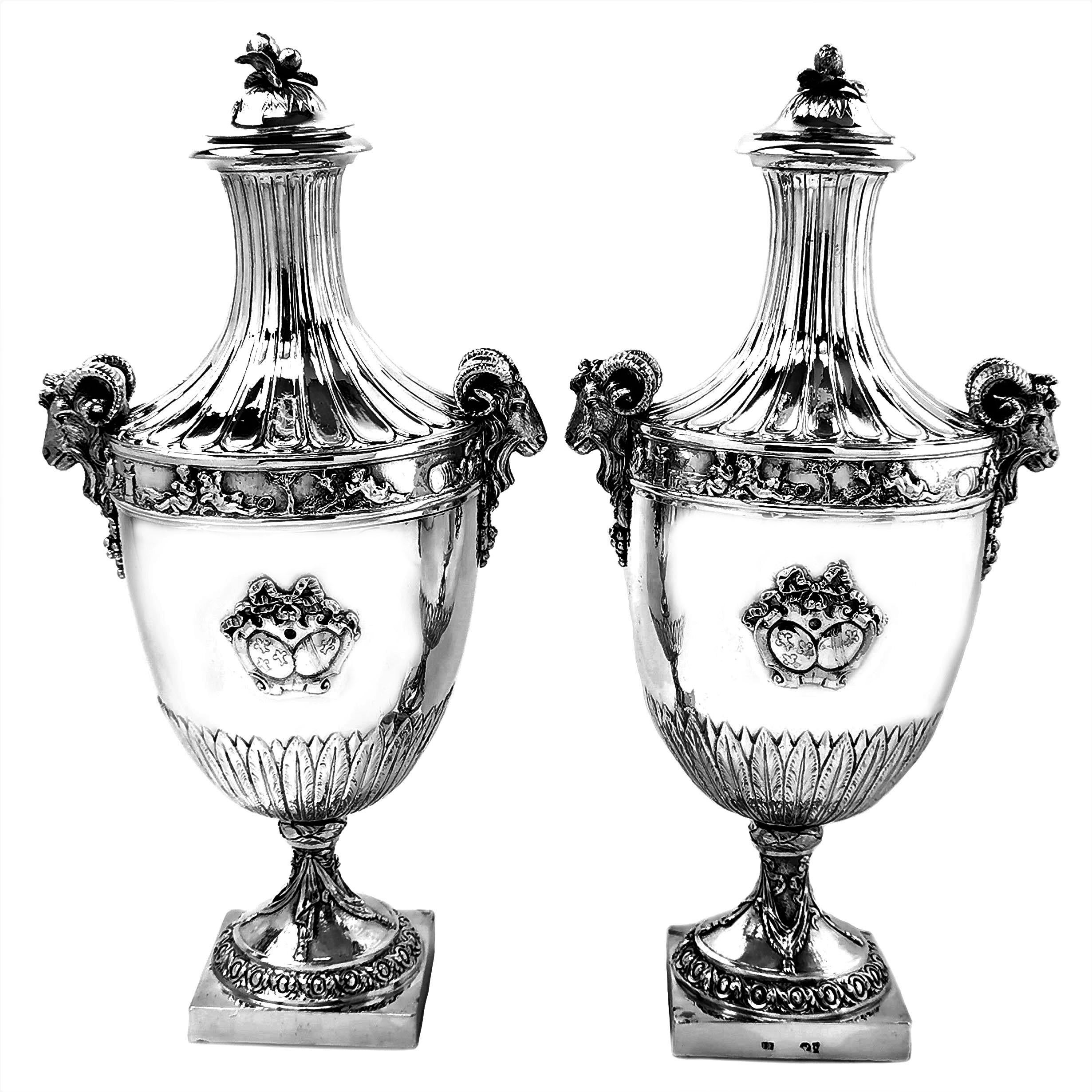 An impressive pair of Antique German solid Silver lidded Vases / Urns on square bases. These Vases are decorated with detailed chased and applied elements including stylized leaves chased around the lower portion of the body. Each Vase has an