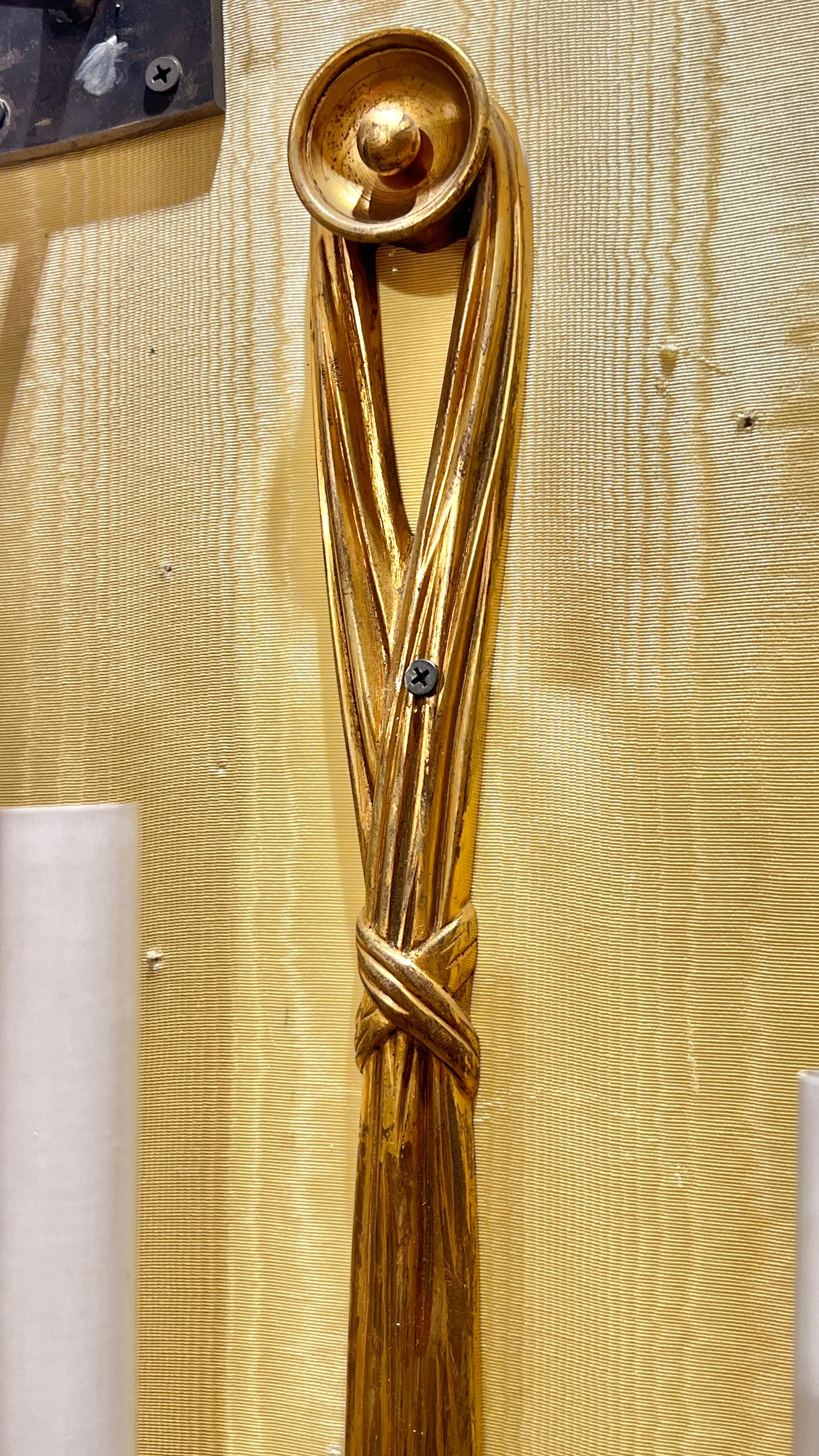 Pair of large antique electrified gilt bronze wall lights (sconces) in the French Louis XV / XVI style in the form of ribbons and tassels, each 31 1/2 inches tall, 12 in wide and 7 in deep, with candelabra size sockets, circular on/off switch,